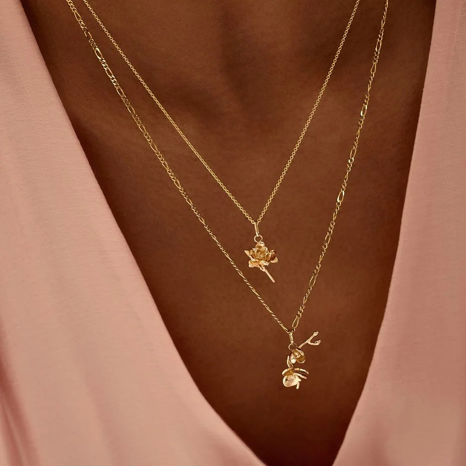 Two gold necklaces with pendants on a woman's chest