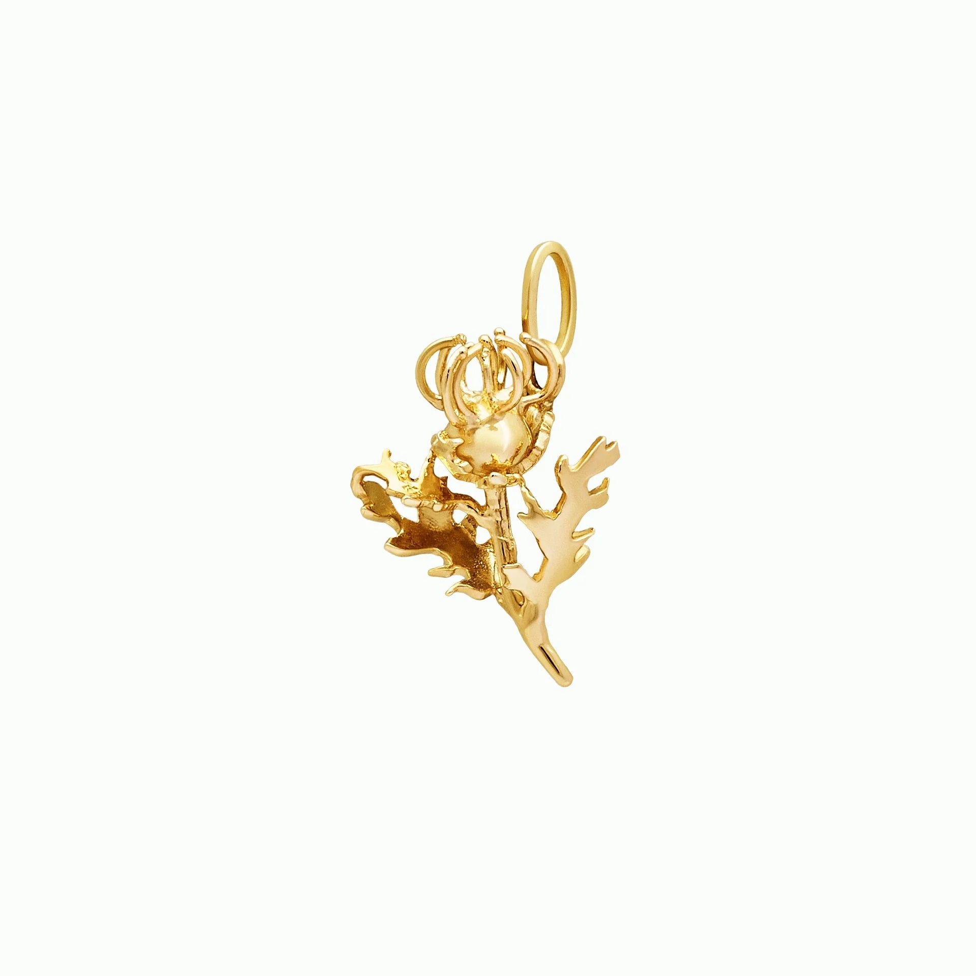 Gold pendant with thistle design on a white background