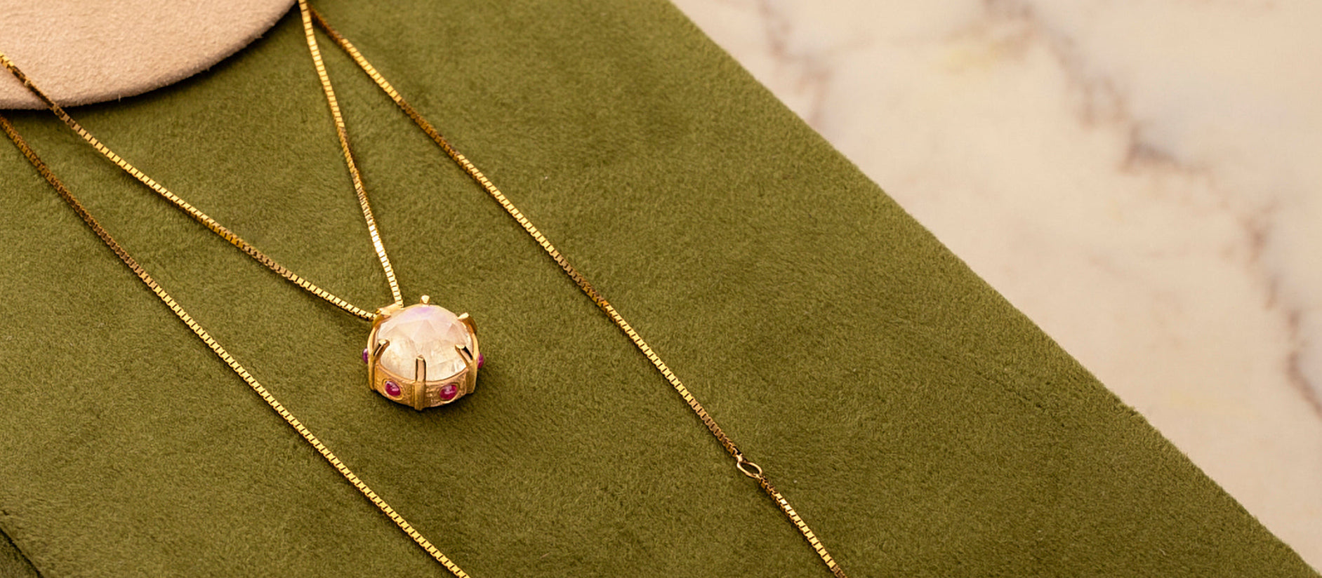 Gold necklace with a pendant on a green fabric background