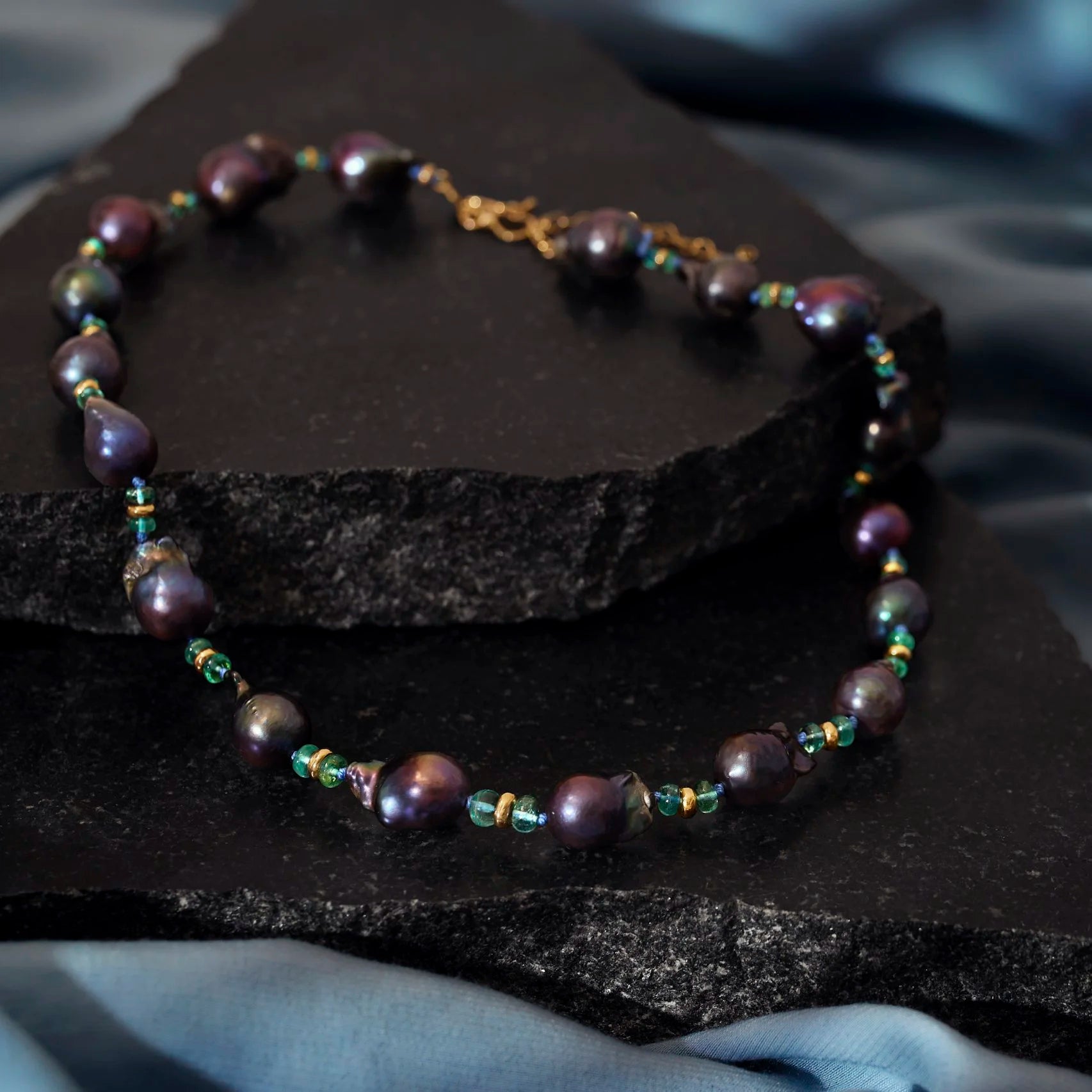 Pearl bracelet with small tourmaline beads on a dark stone surface