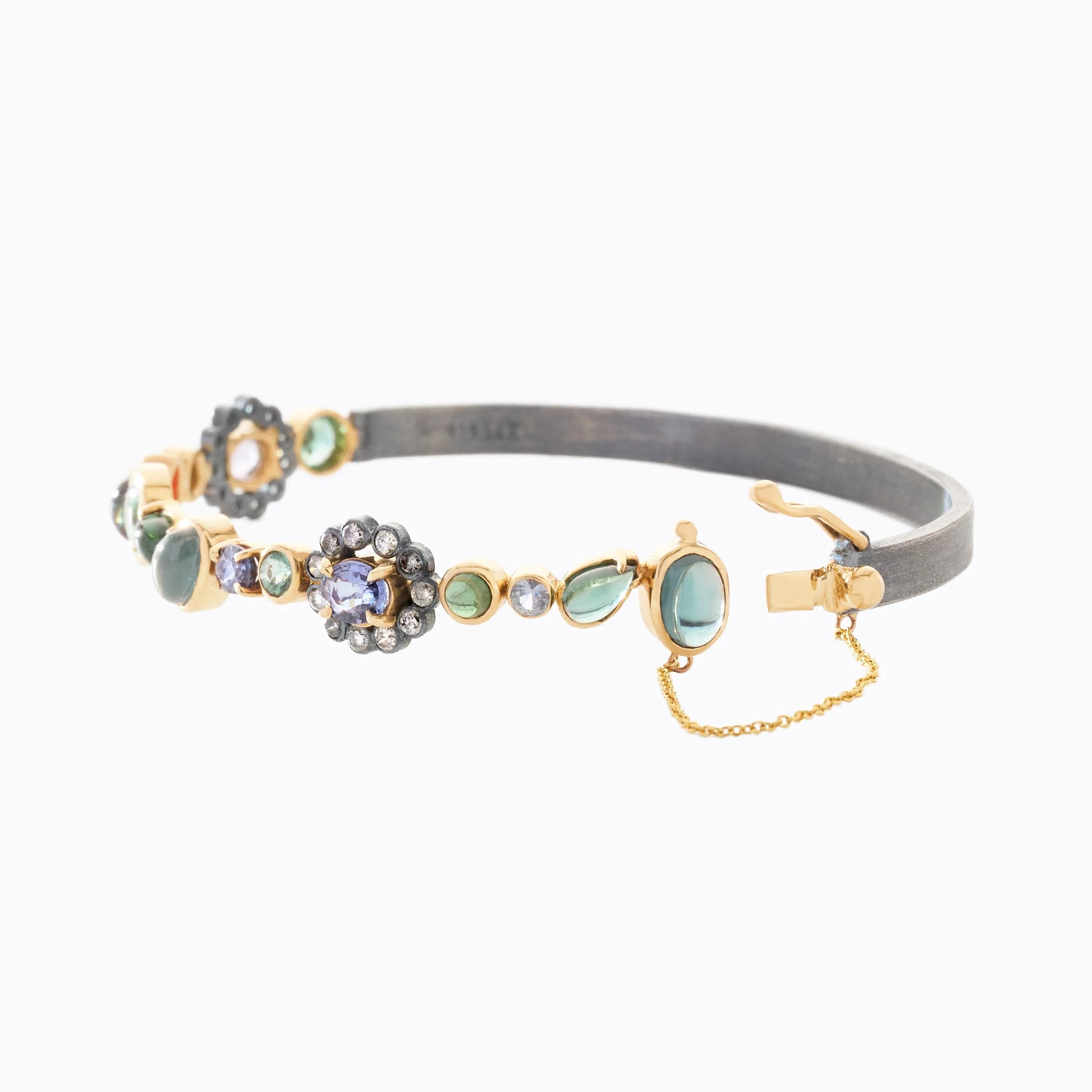 Gray and gold hinged cuff with decorative gemstones on a white background