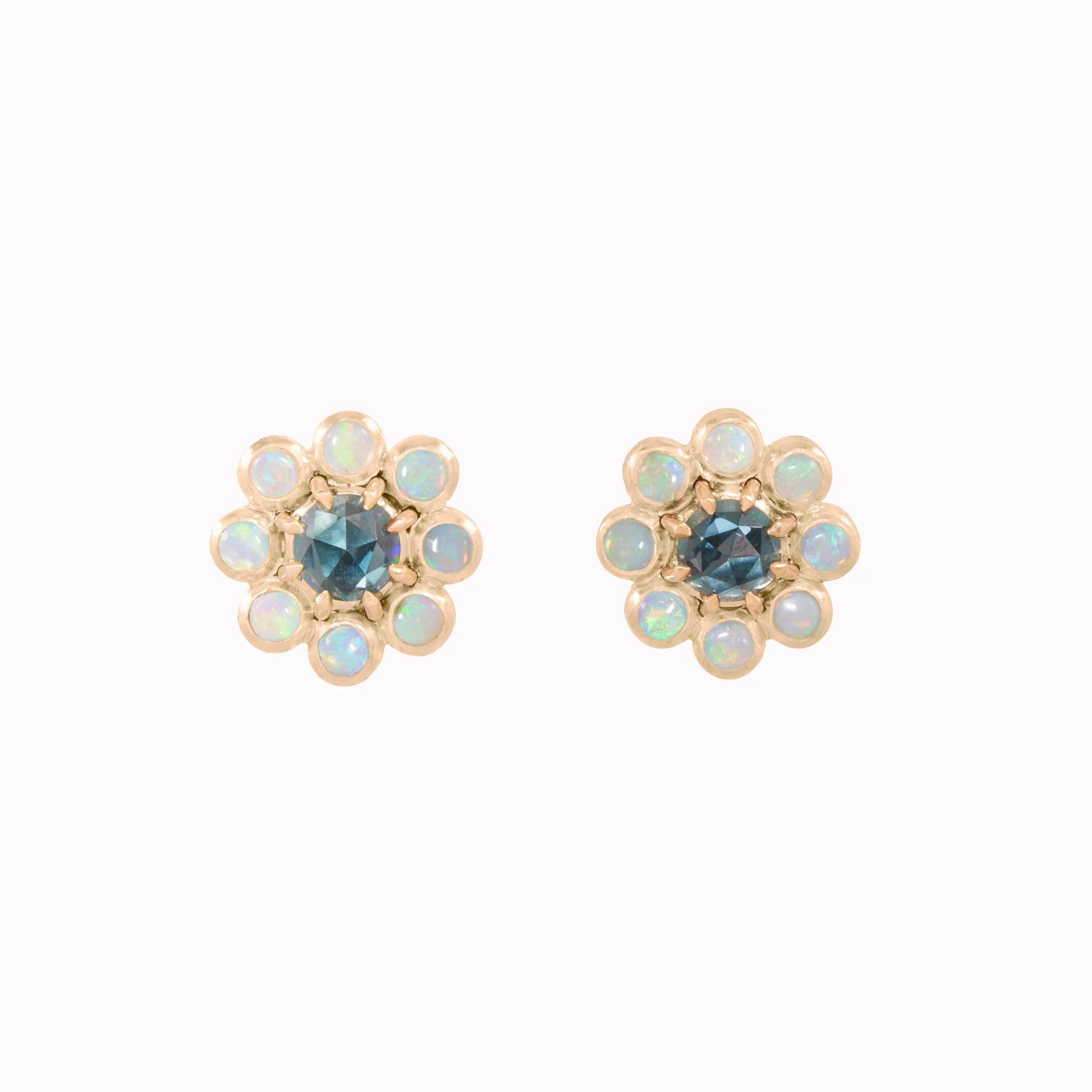 Pair of flower-shaped earrings with central blue gemstones on a white background