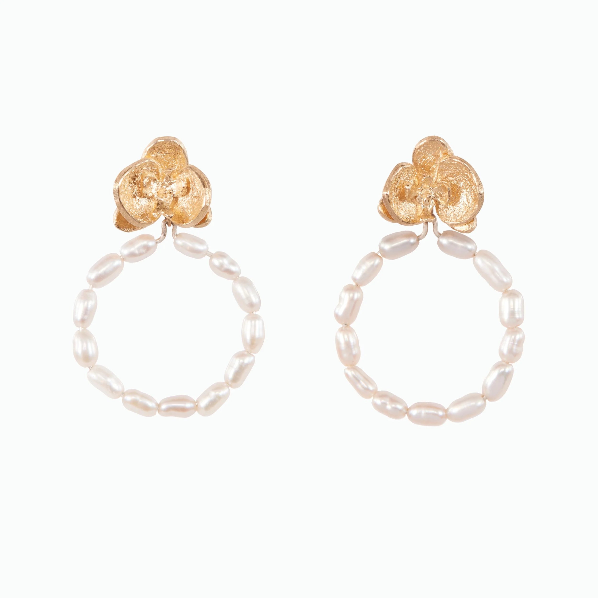 Pair of hoop earrings with gold floral tops and pearl beads on a white background