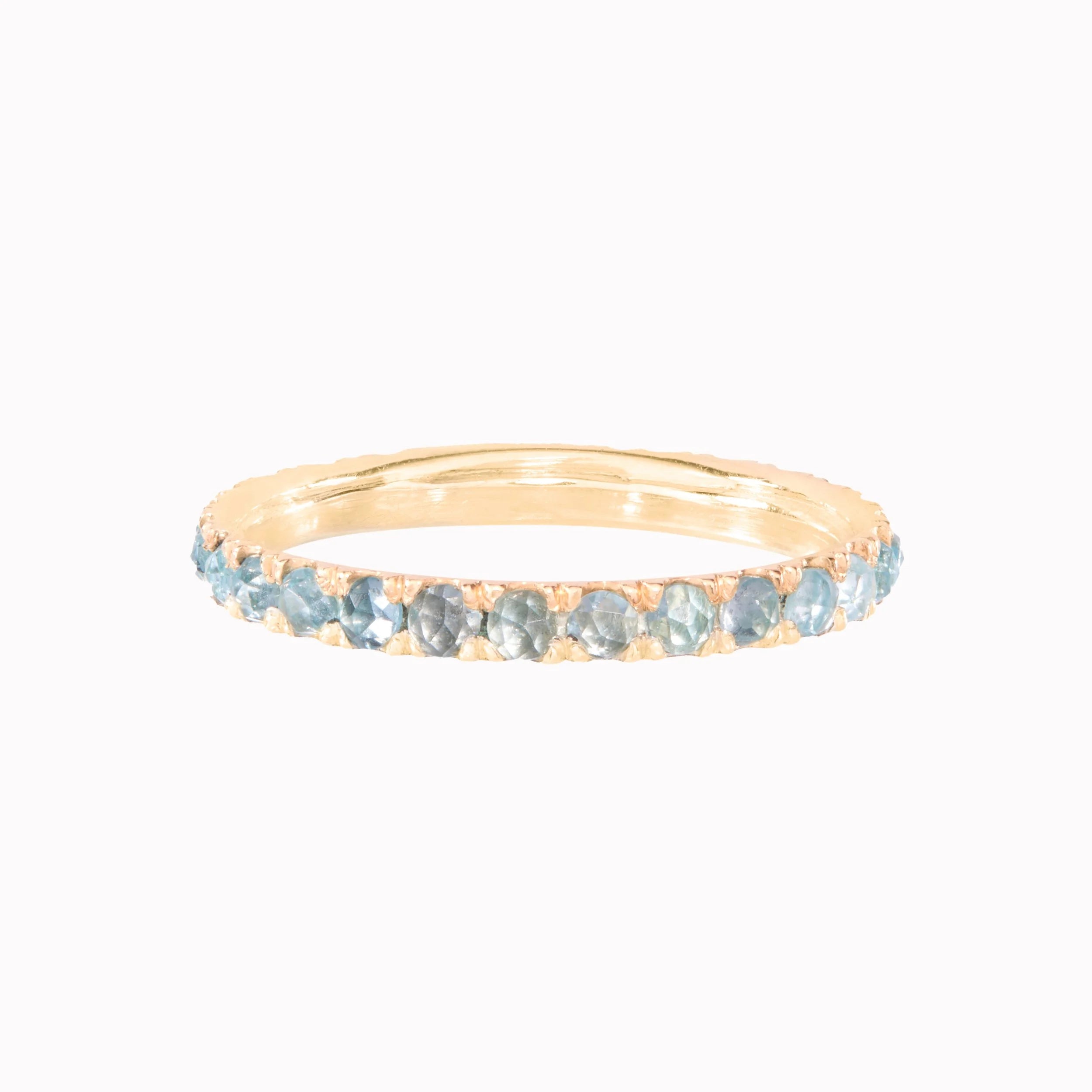Gold ring with small blue stones on a white background