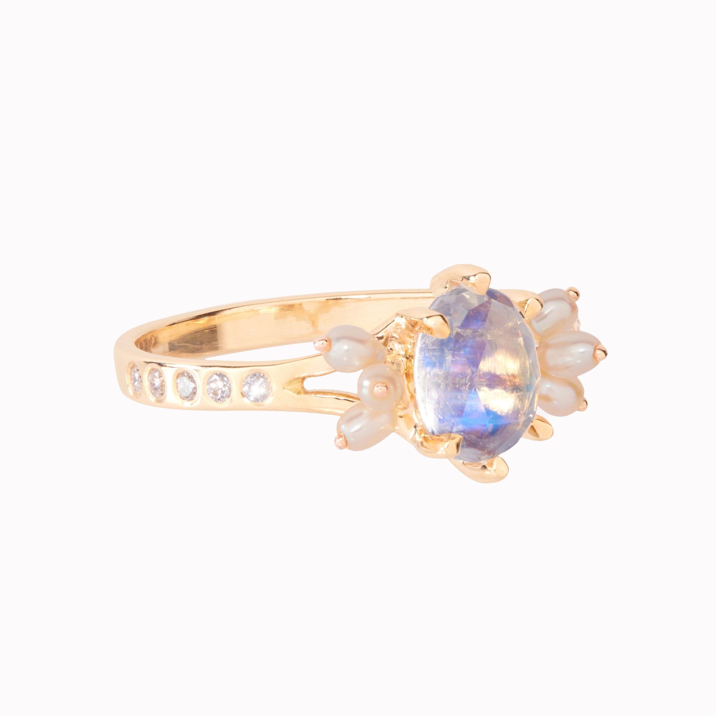 Gold ring with a moonstone and pearl accents on a white background
