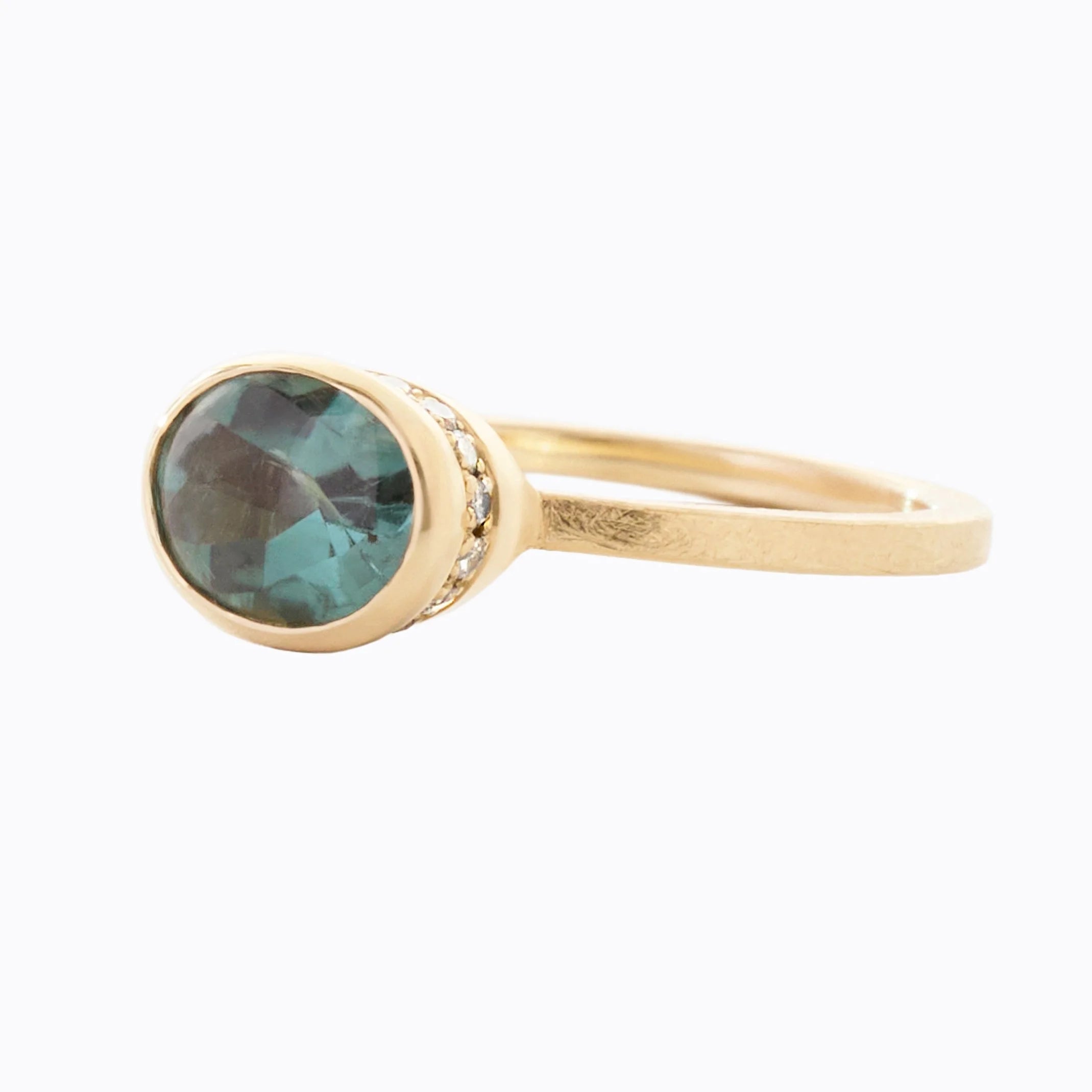 Gold ring with a teal gemstone on a white background