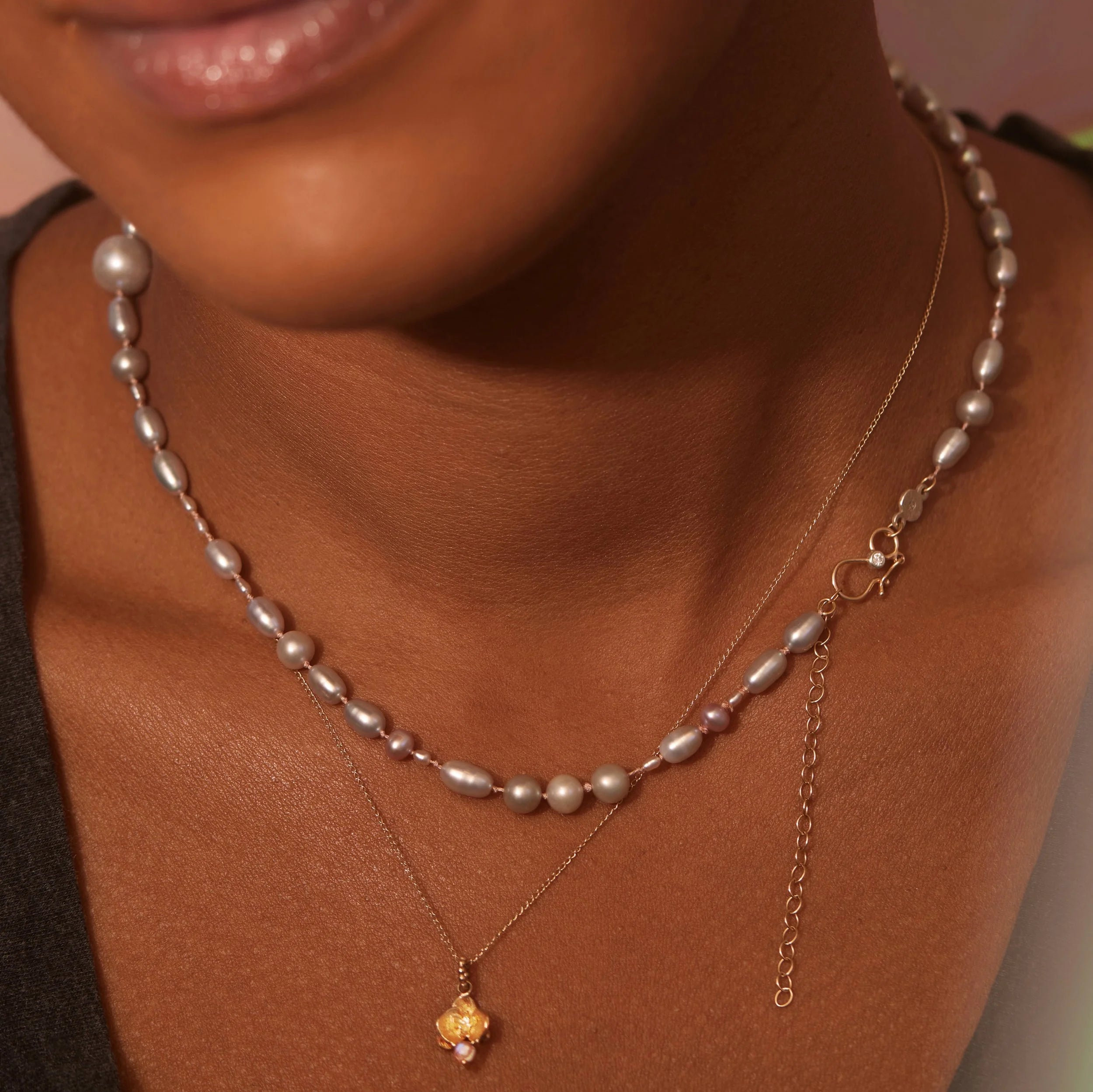 Close-up of a person wearing a pearl necklace with a gold pendant.