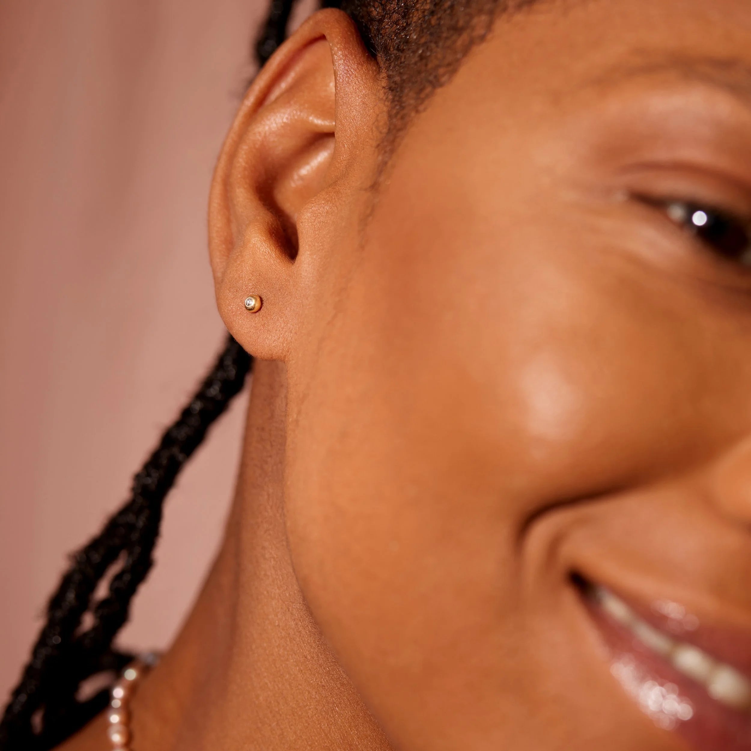 Close-up of a woman wearing a gold earring with a blurred background