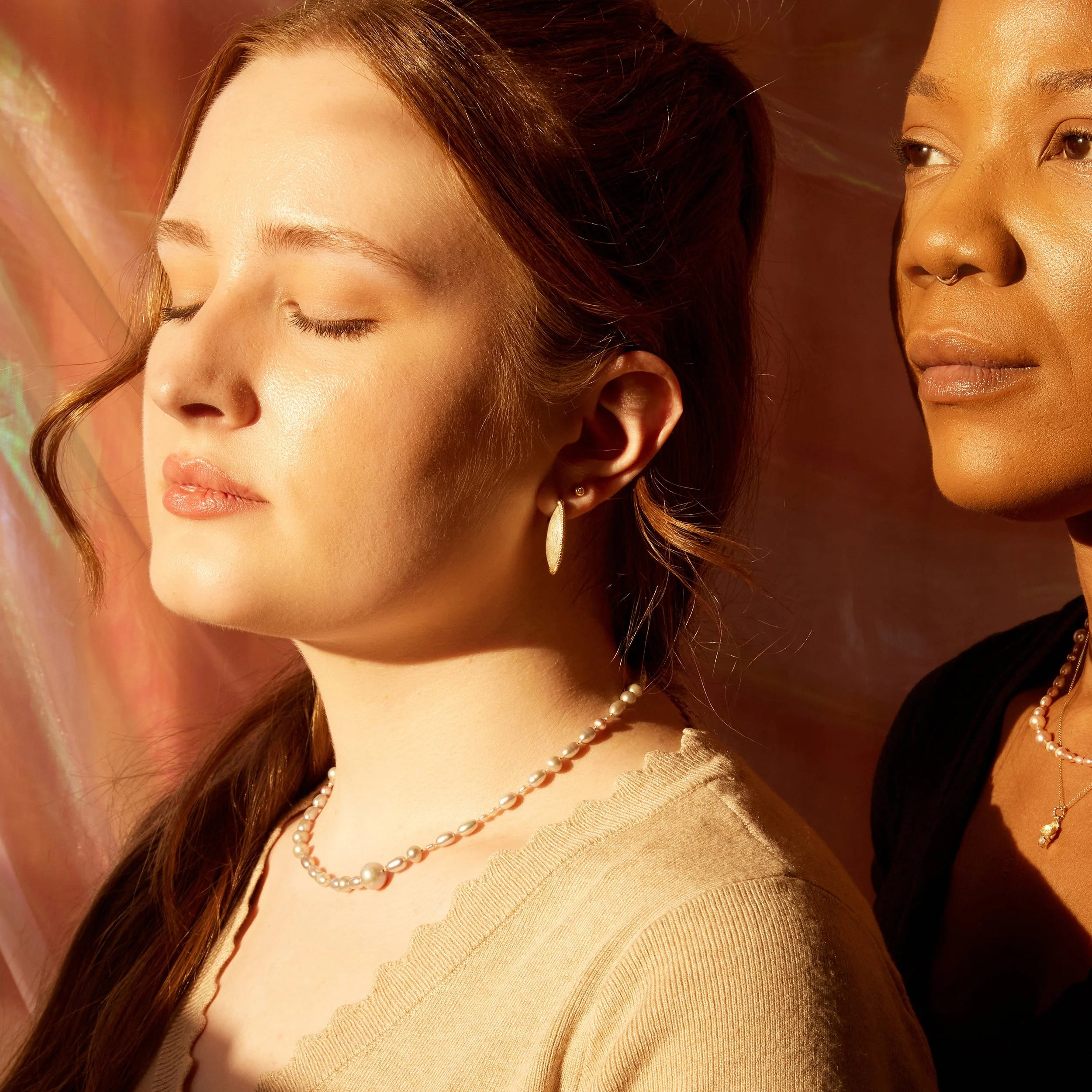 Two women standing close together with a warm, soft-focus background