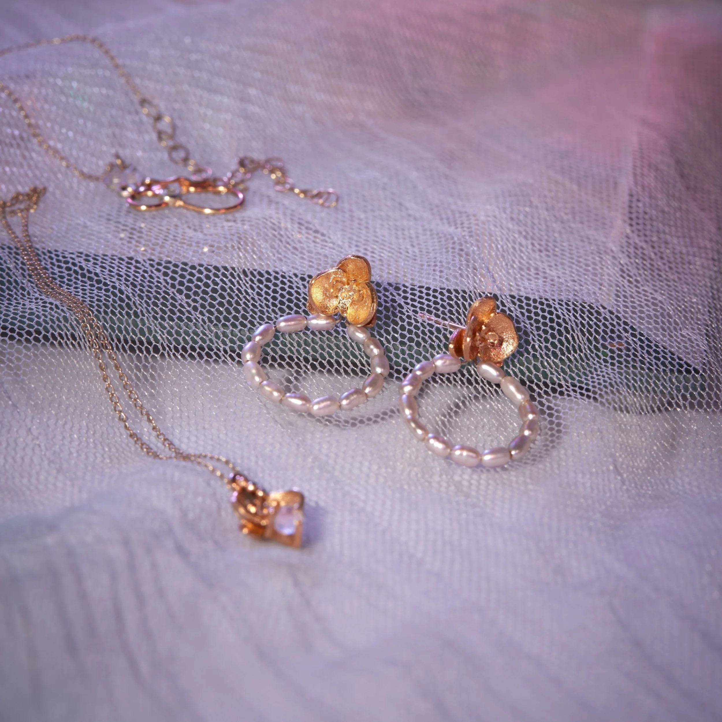 Jewelry set with gold and pearl earrings on a soft fabric background
