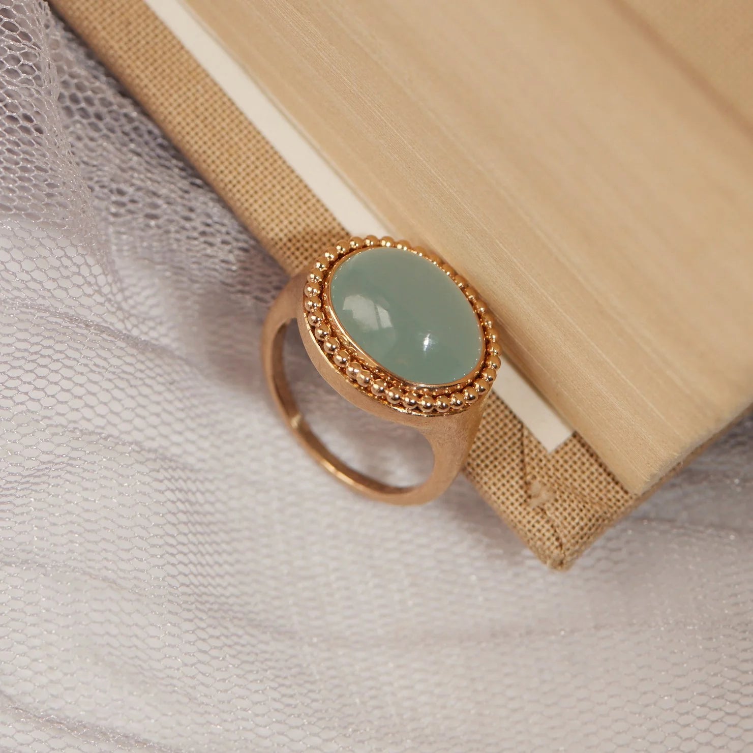 Gold ring with a light blue gemstone on a textured fabric background