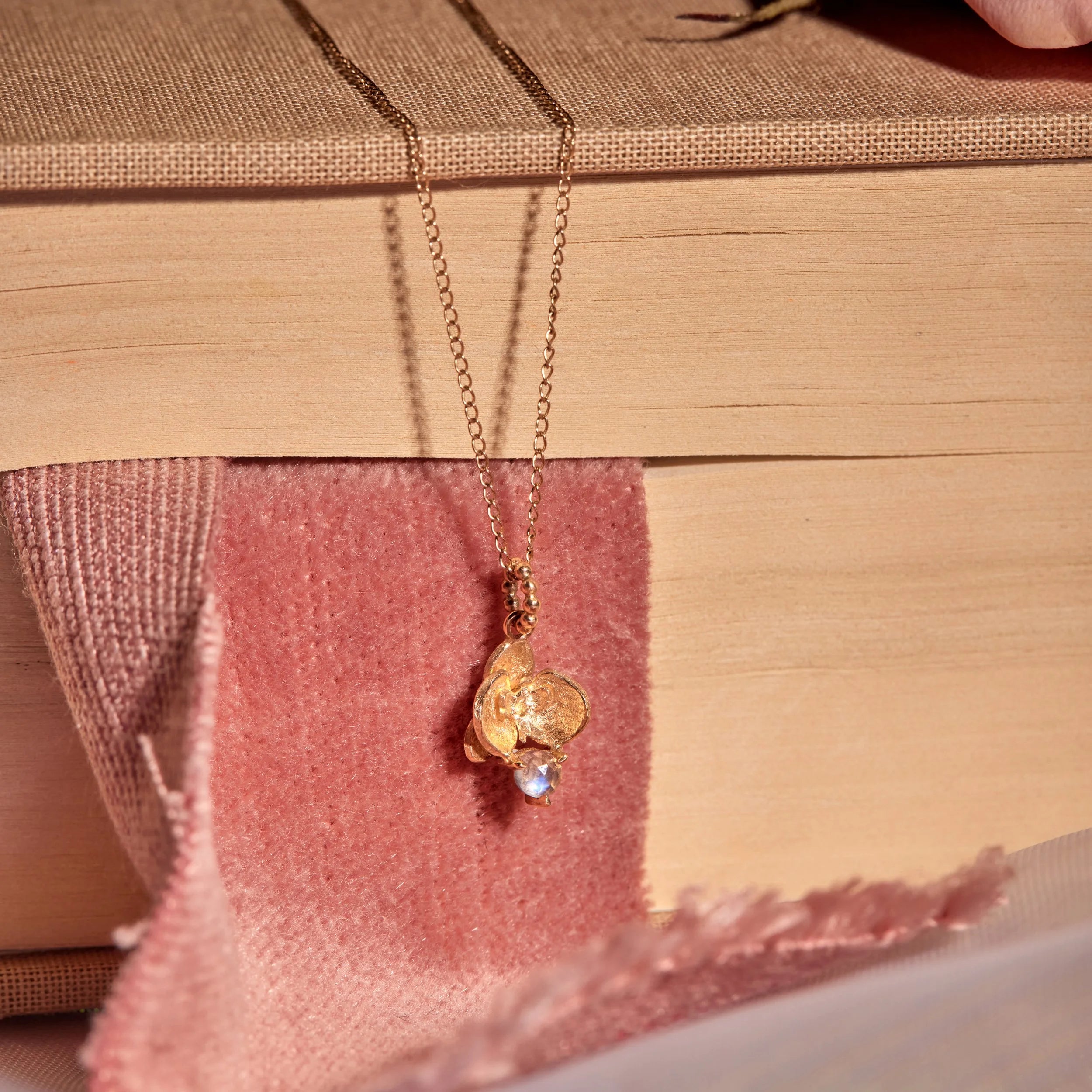 Gold necklace with a pendant on a textured surface