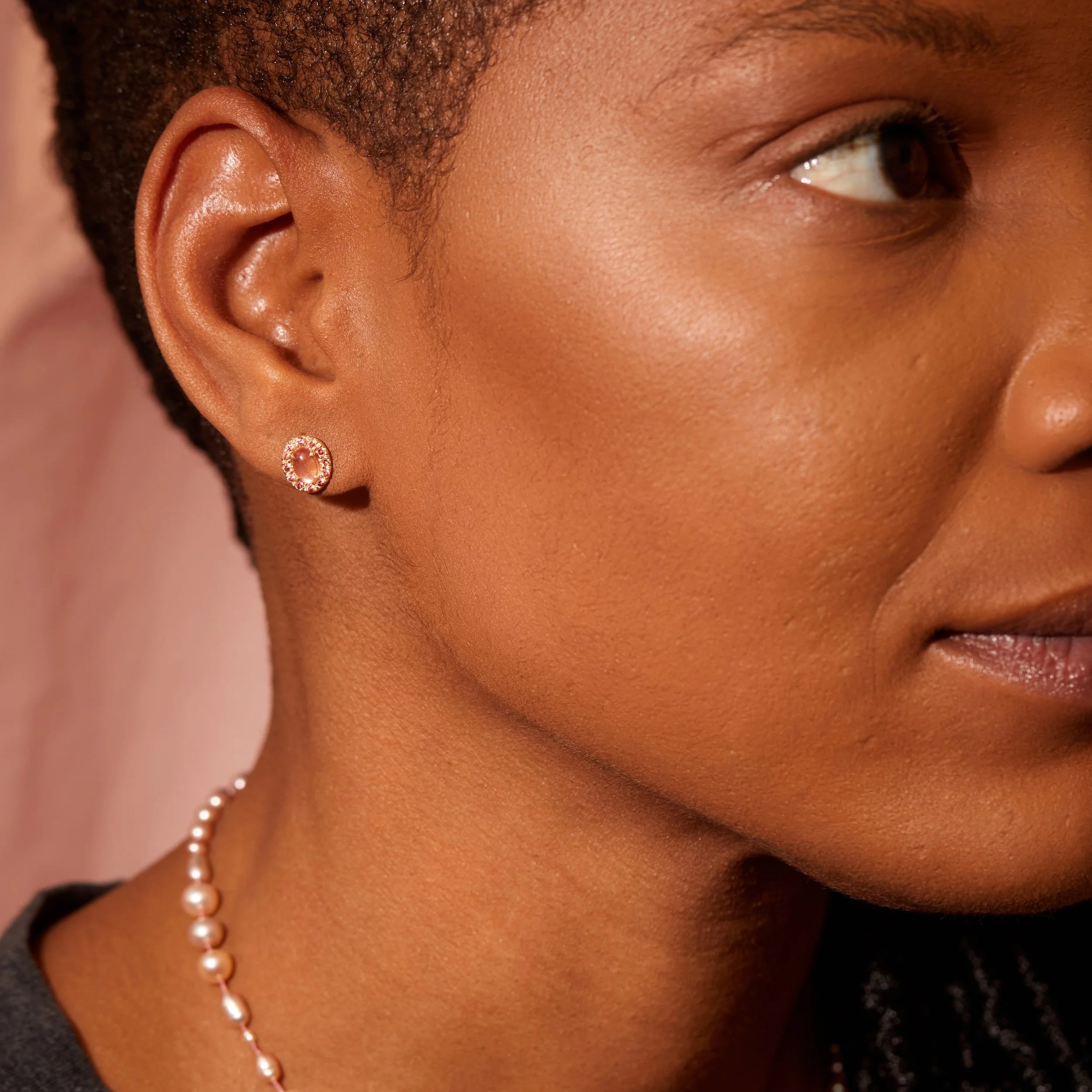 Close-up of a woman's face wearing earrings and a necklace with a soft background