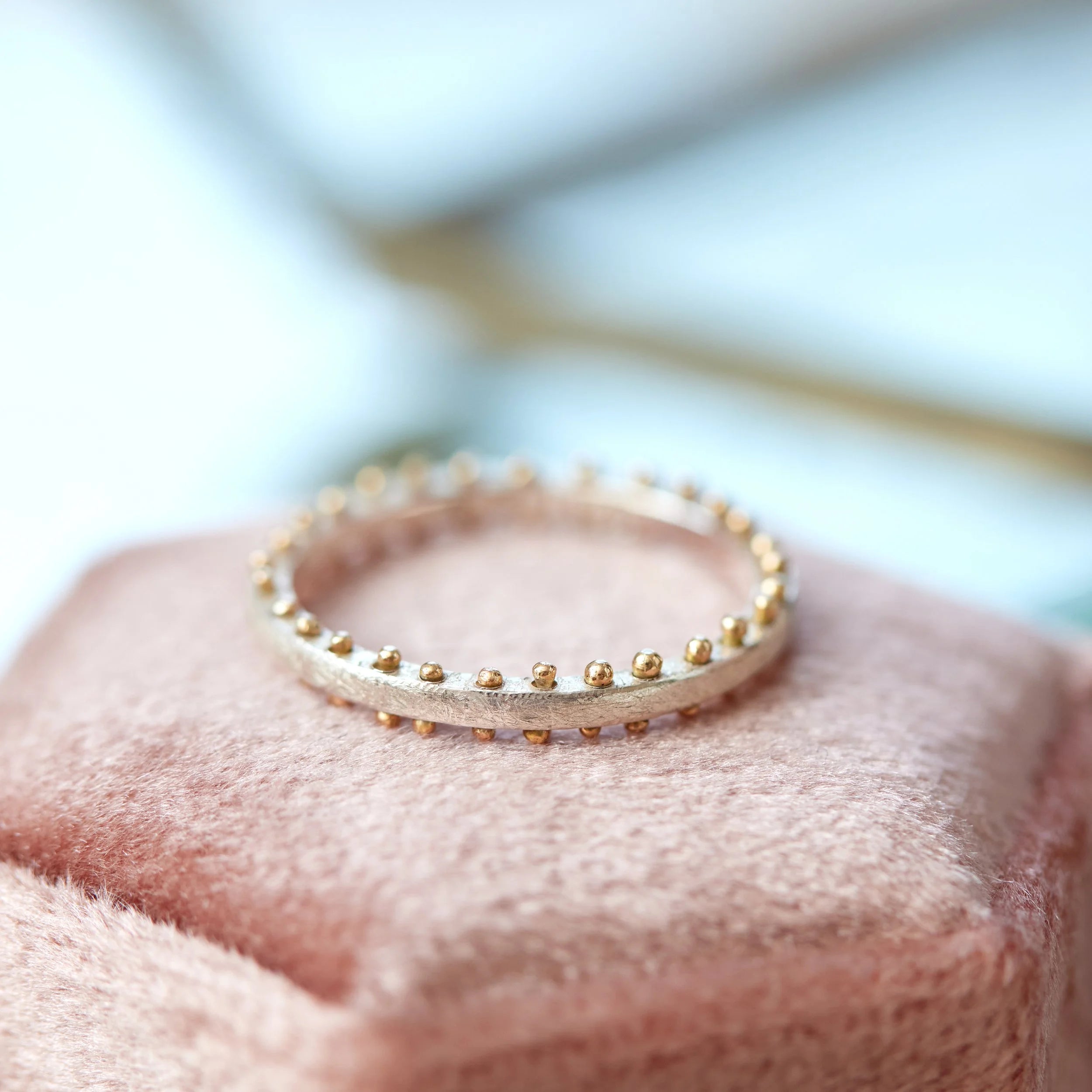 Gold and silver ring on a soft pink fabric background