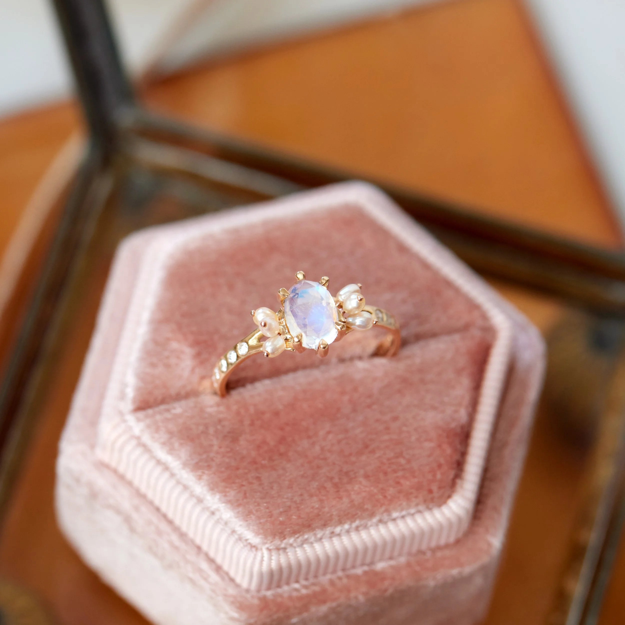 Gold ring with a central gemstone on a pink velvet cushion