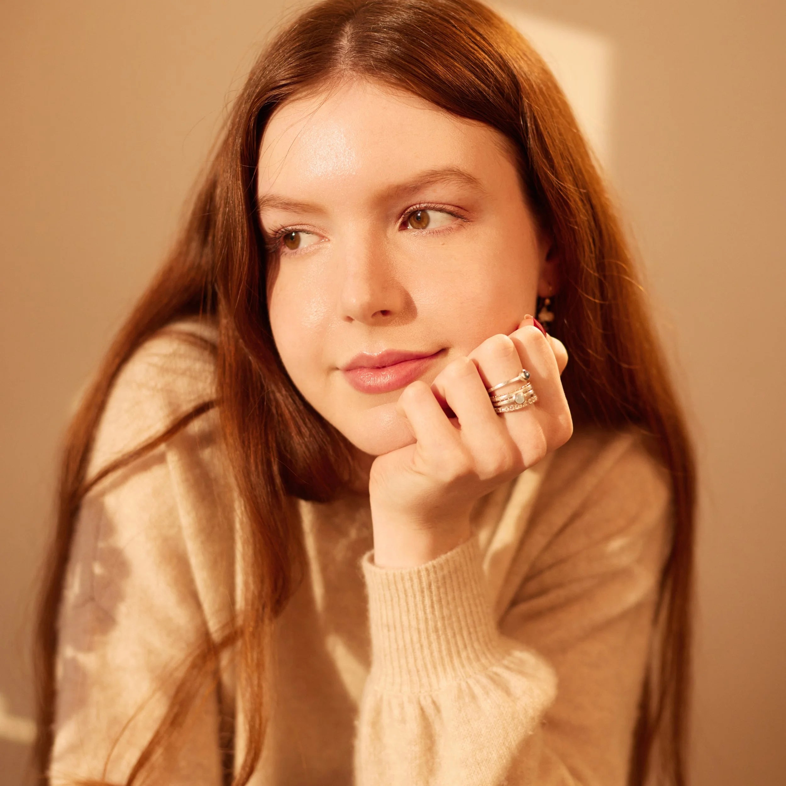 Woman wearing a beige sweater with a blurred background