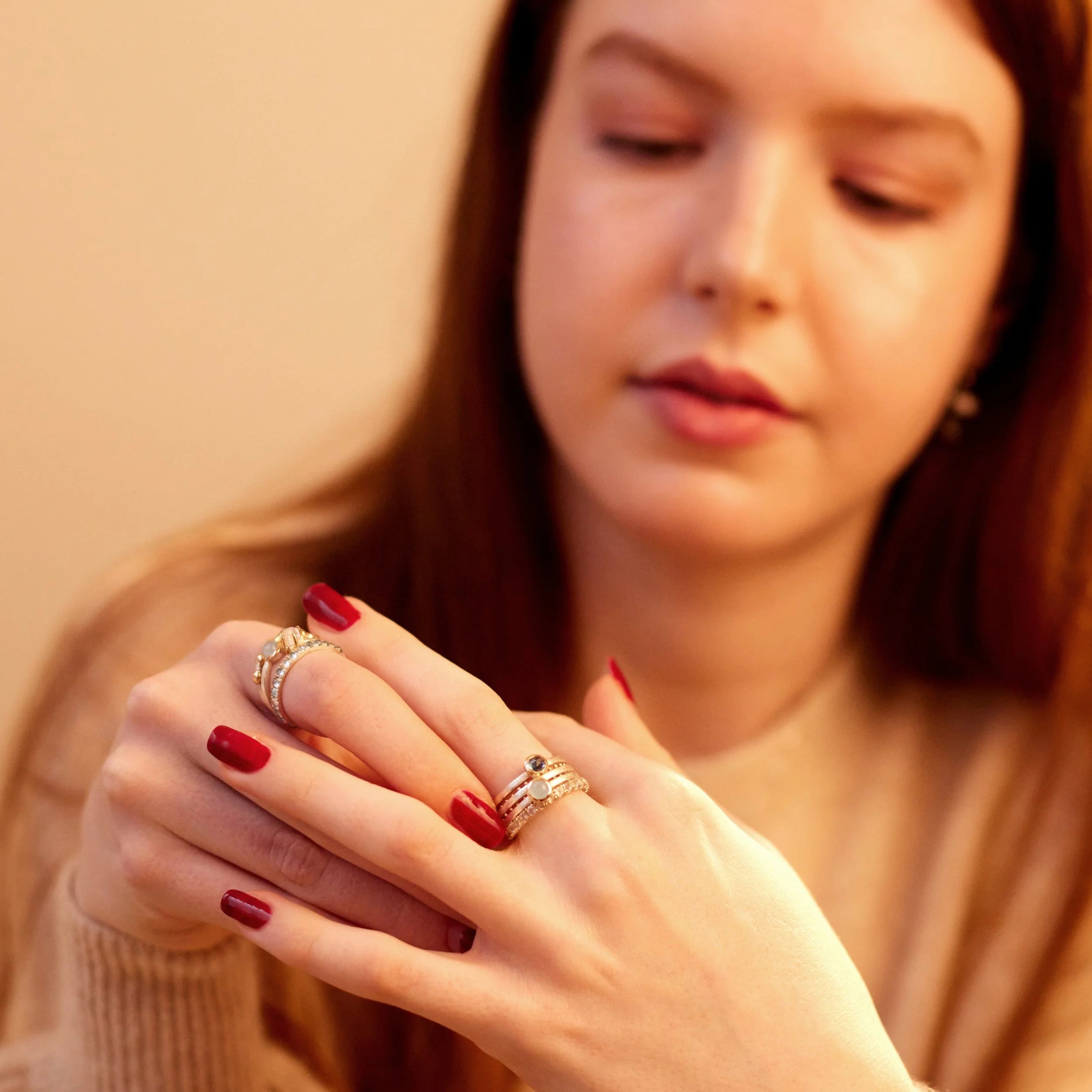 Woman wearing multiple rings on her fingers with a neutral background