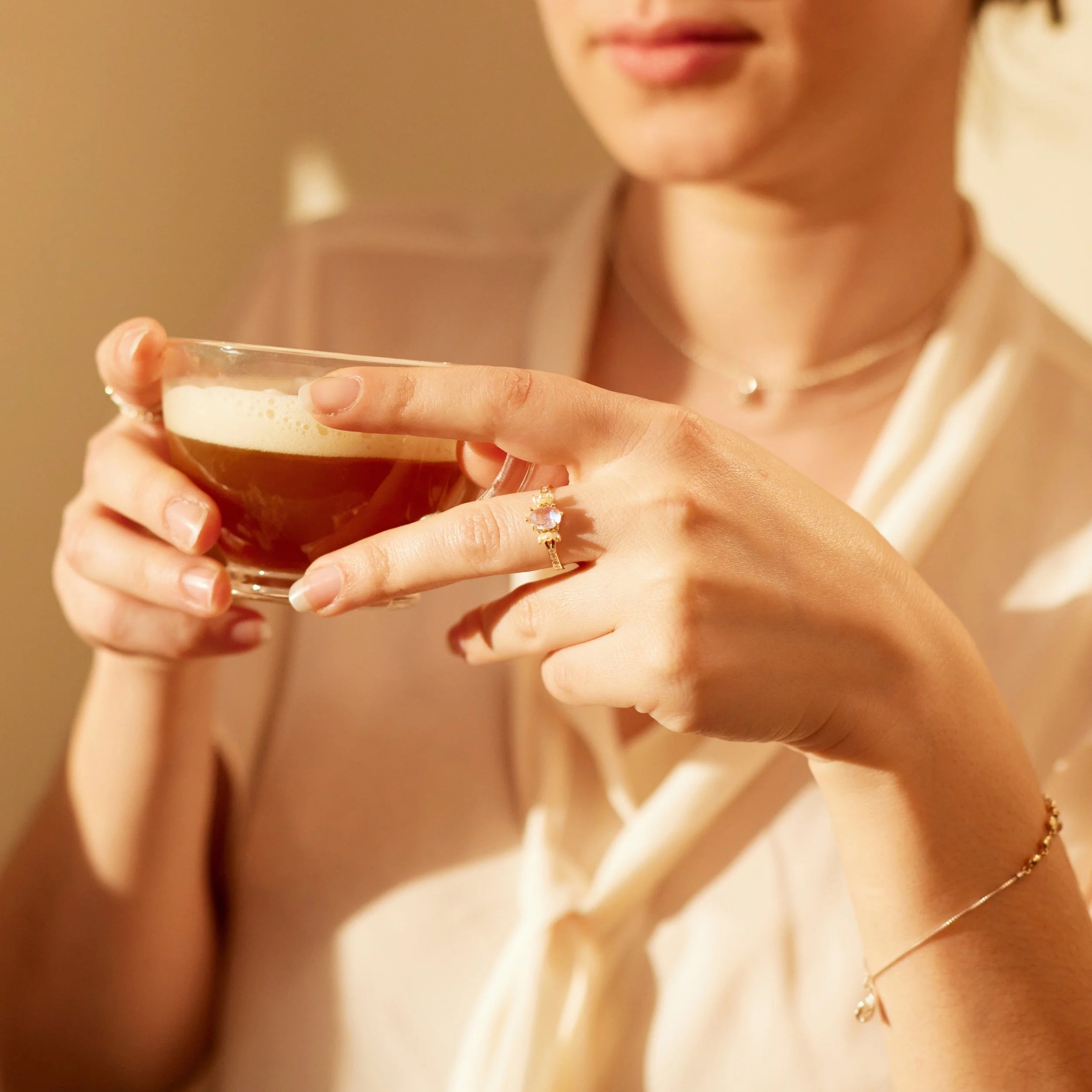Person holding a glass of espresso and ring with a blurred background