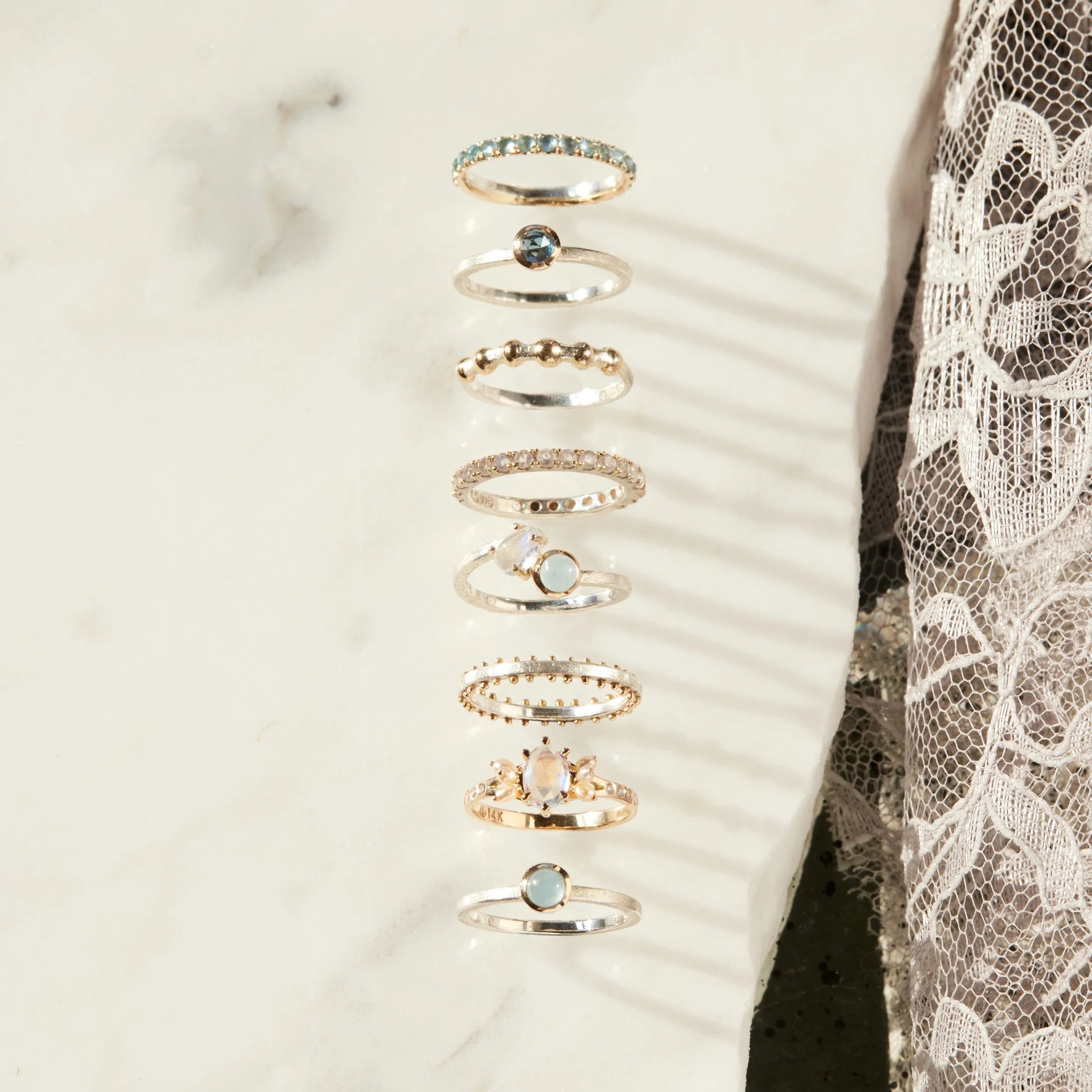 Set of gold rings with gemstones on a white slab and lace background