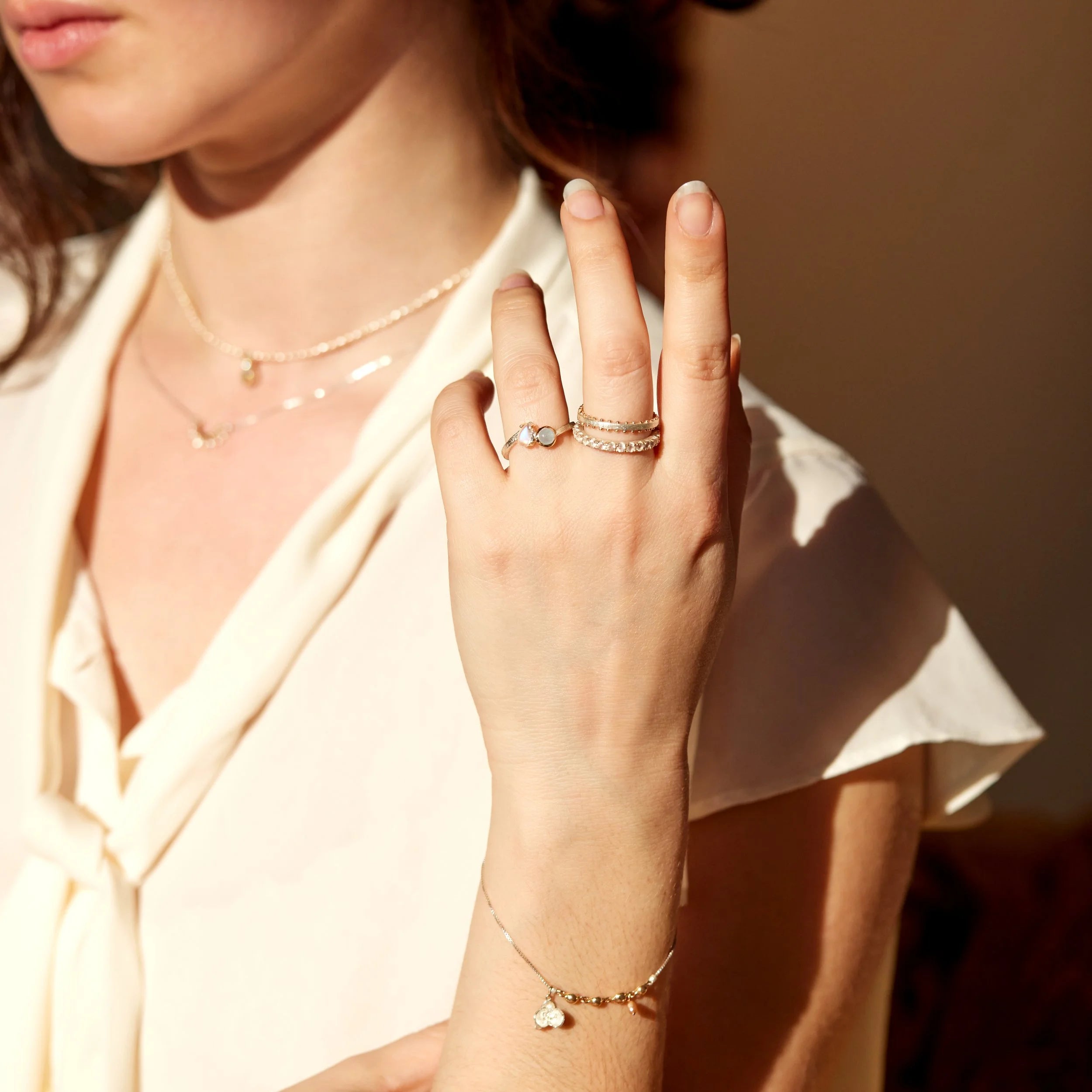 Close-up of a person's hand wearing multiple rings with a soft background