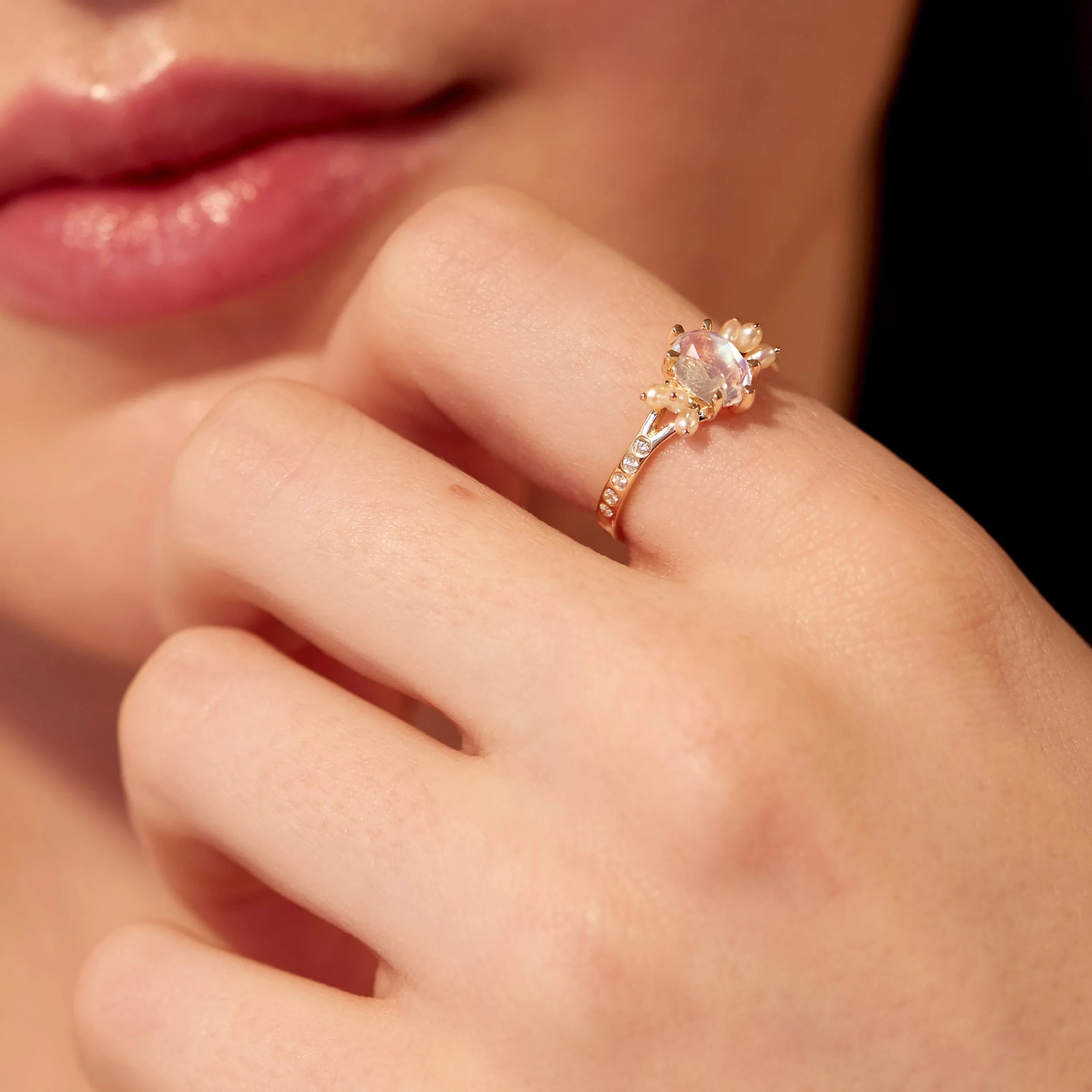 Close-up of a hand wearing a gold ring with a pink gemstone.