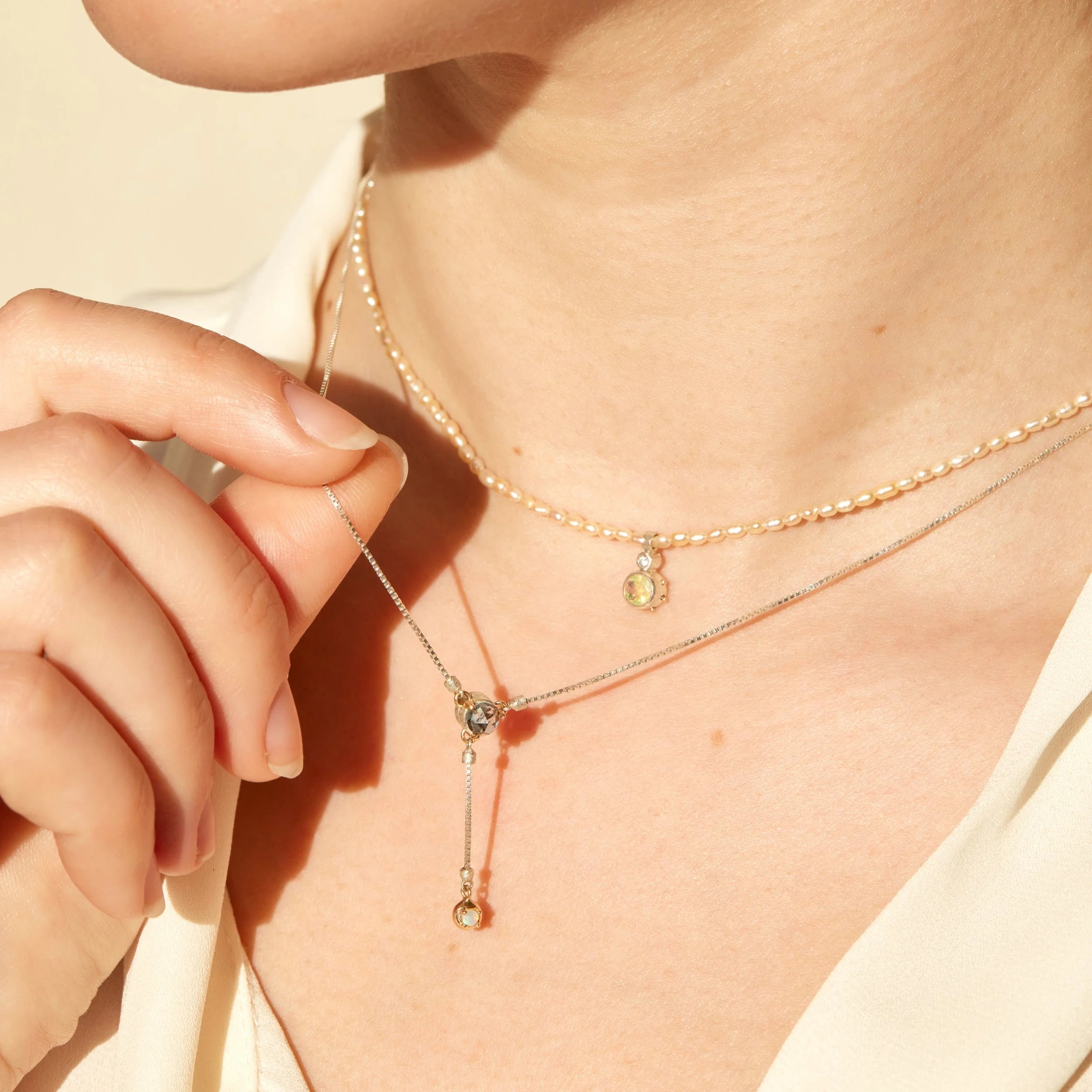 Close-up of a person wearing multiple gold necklaces with small pendants.