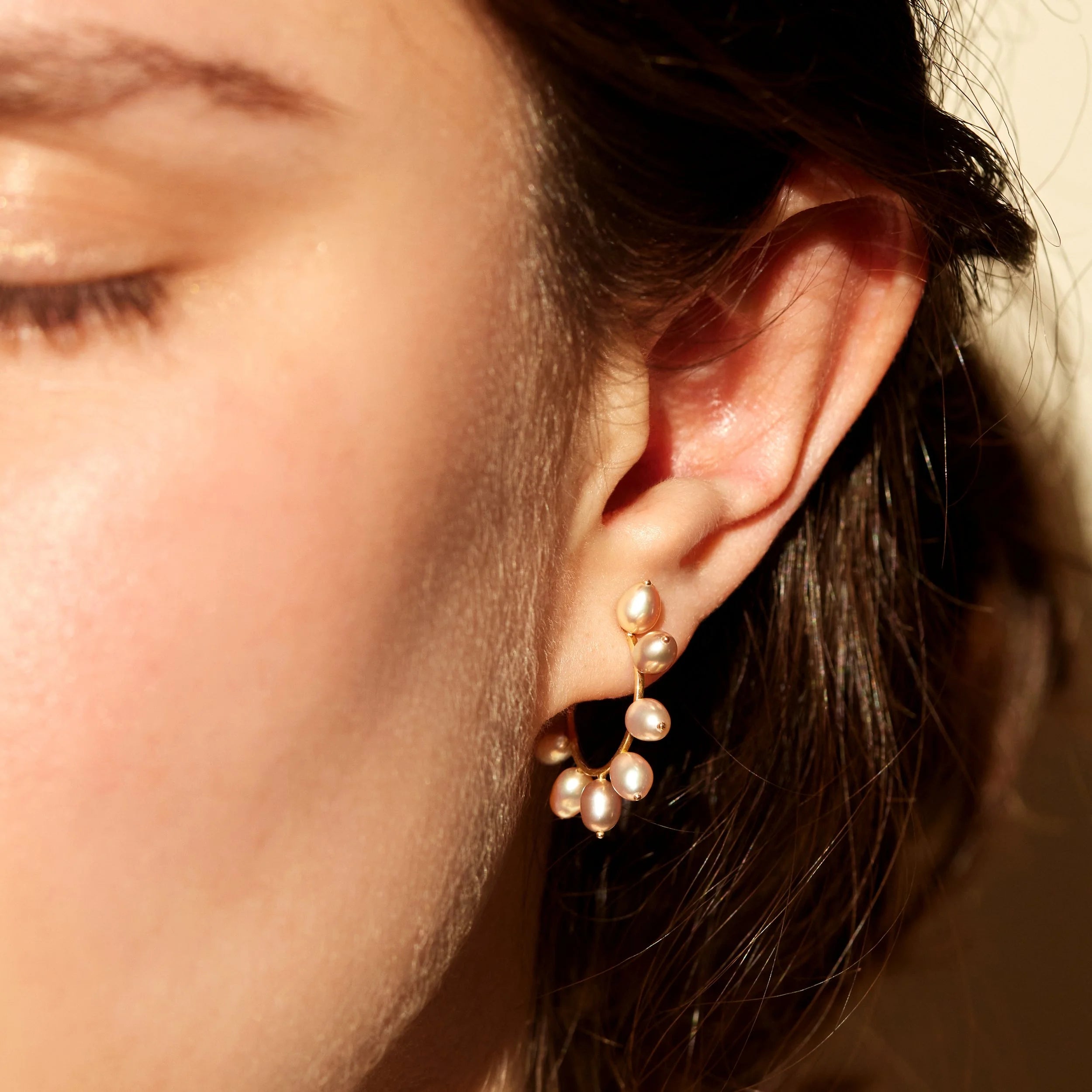 Close-up of an ear wearing a pearl earring with a blurred background