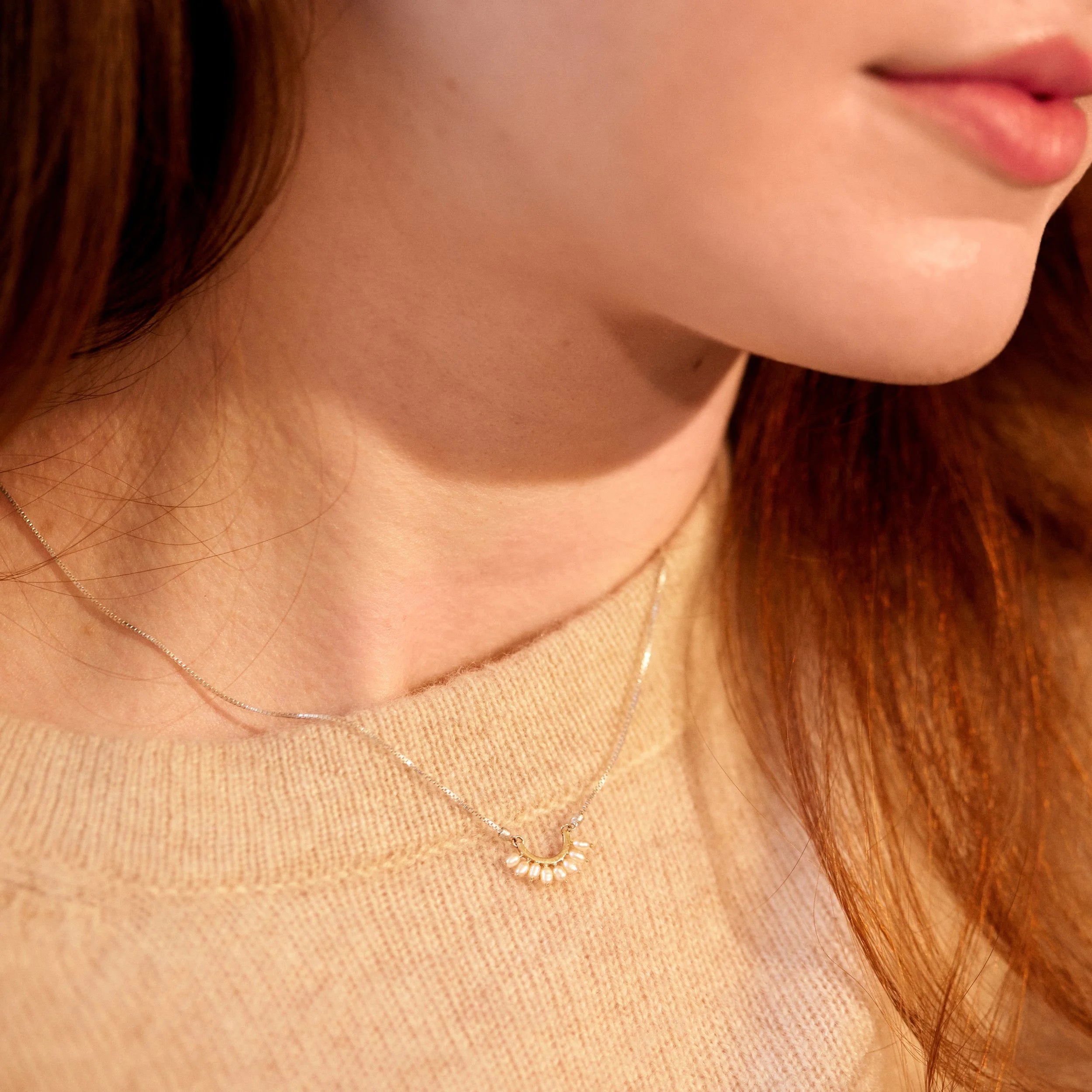 Close-up of a person wearing a delicate gold necklace with a small pendant.