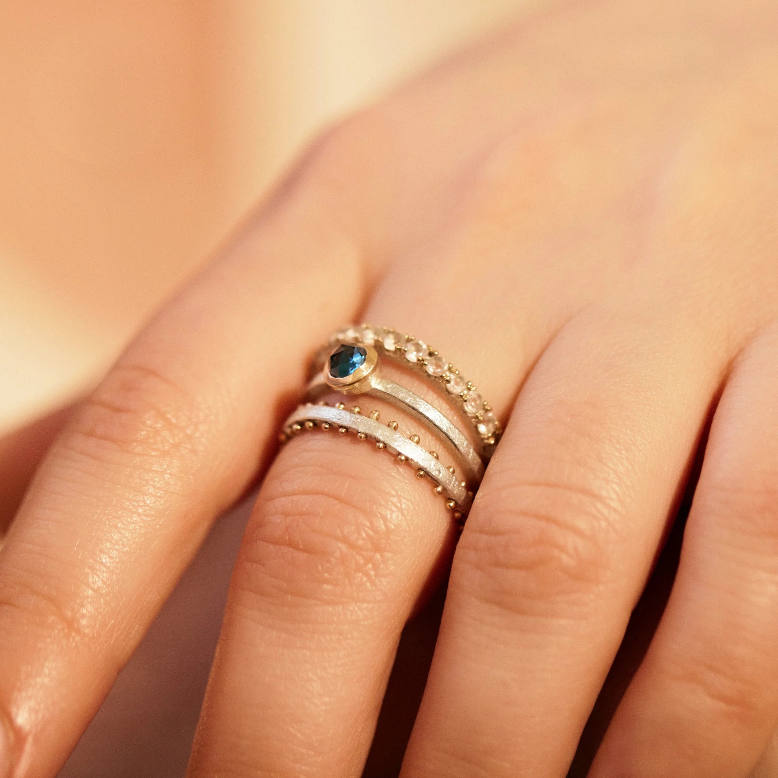Close-up of a hand wearing multiple rings with a soft background