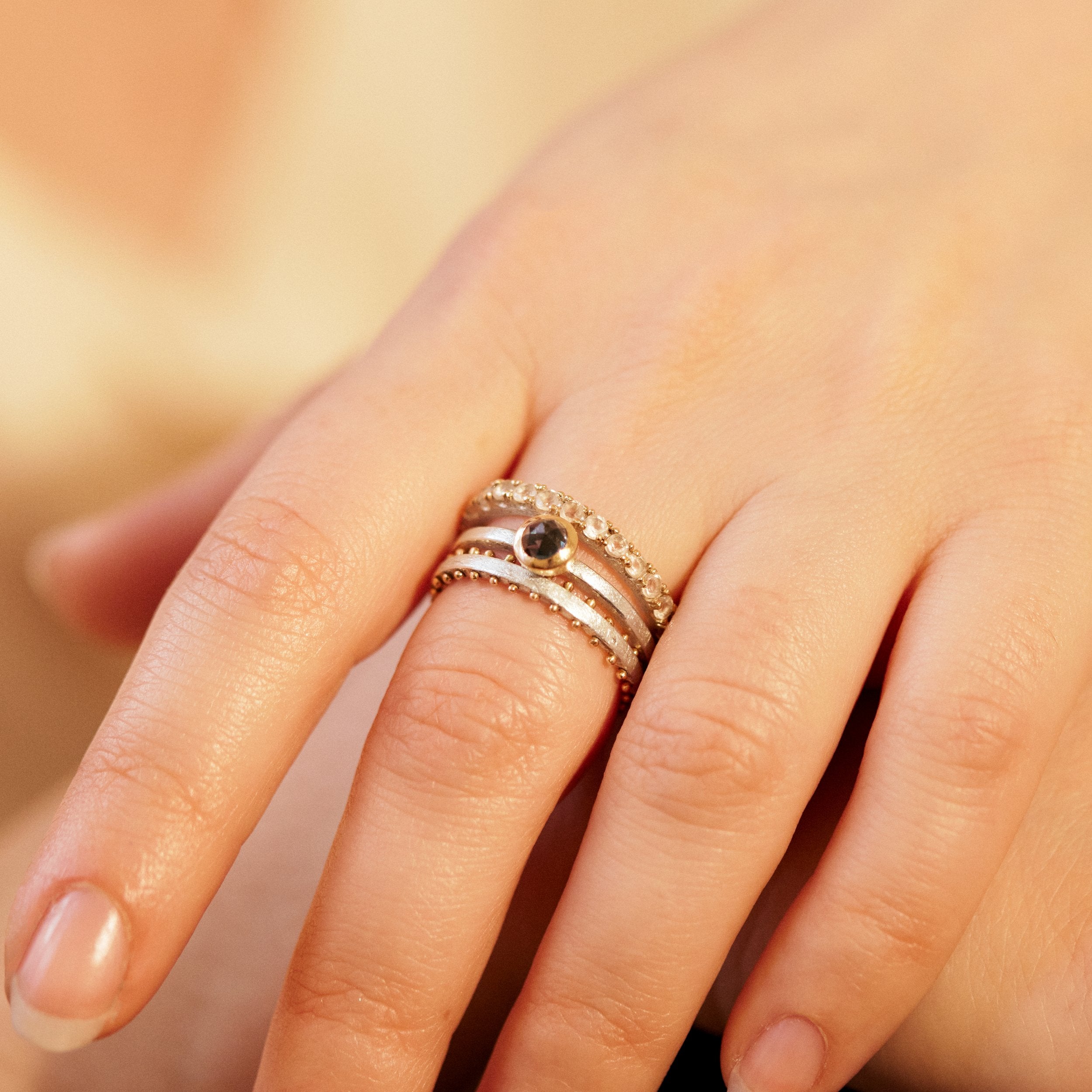 Close-up of a hand wearing three rings with a blurred background