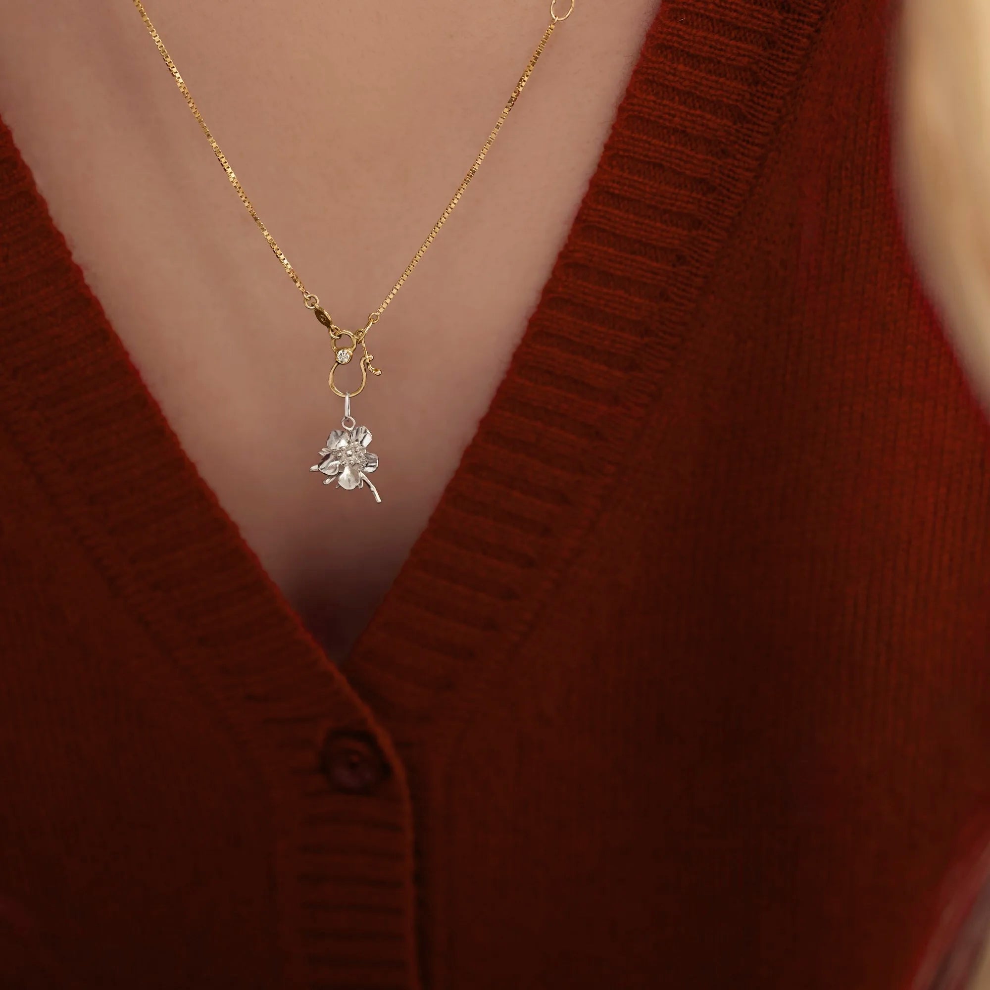 Necklace with a silver pendant worn by a person in a red sweater.