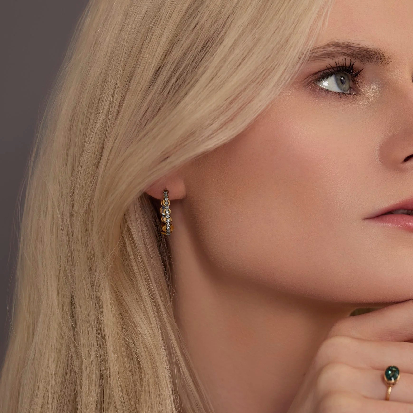 Close-up of a woman wearing gold hoop earrings with small diamonds.