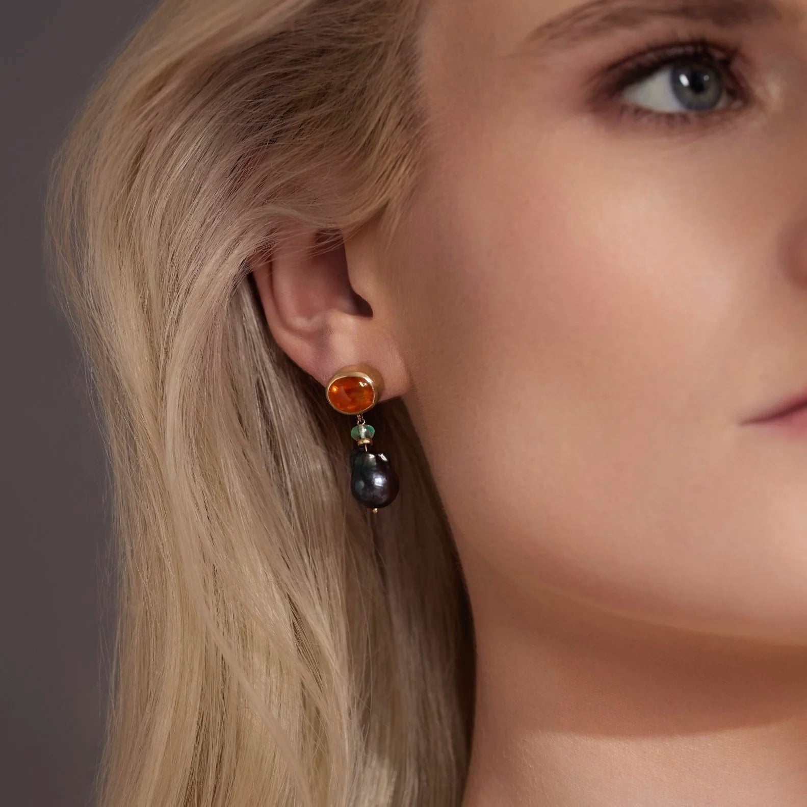 Close-up of a woman wearing a pair of earrings with a neutral background