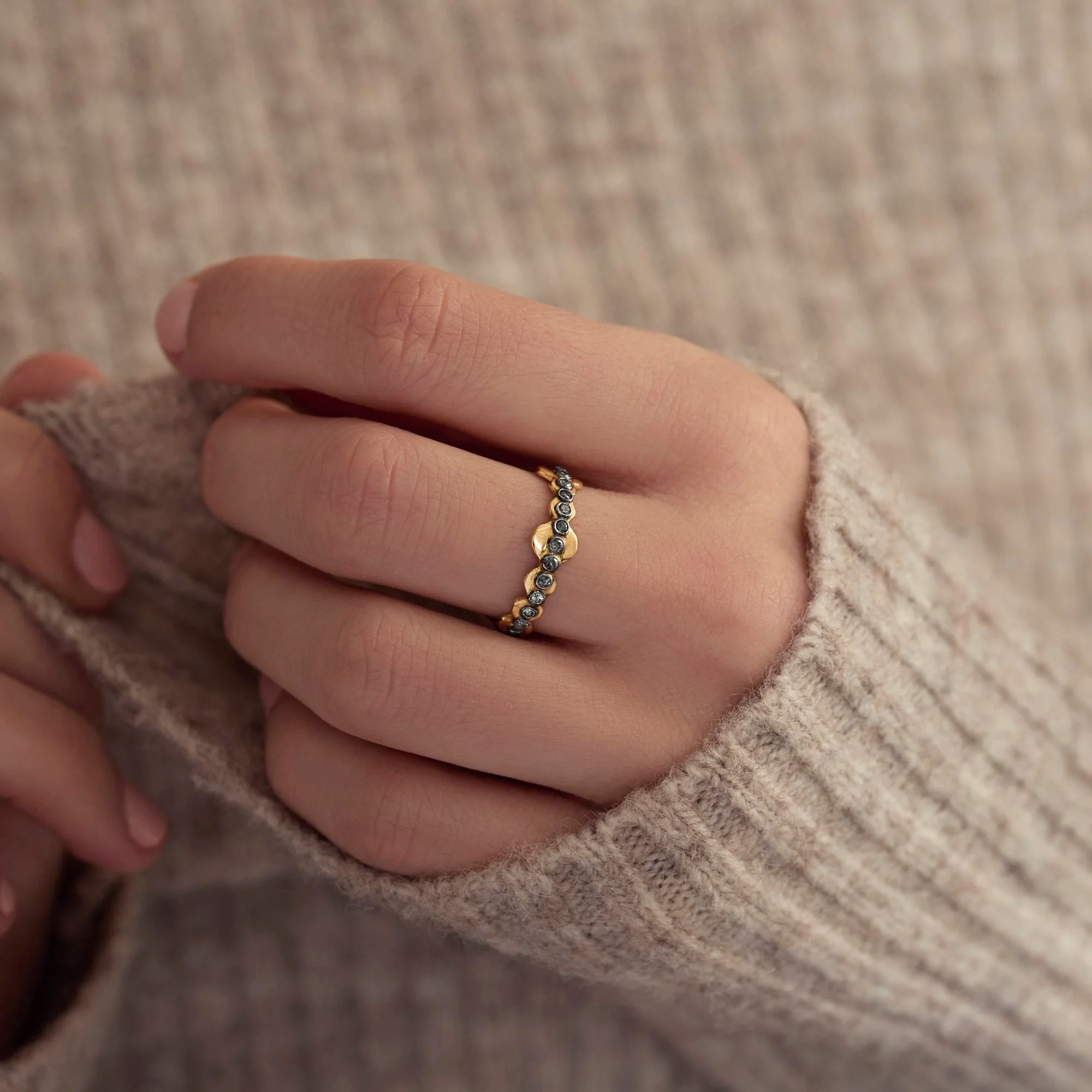 Close-up of a hand wearing a gold ring with a blurred background