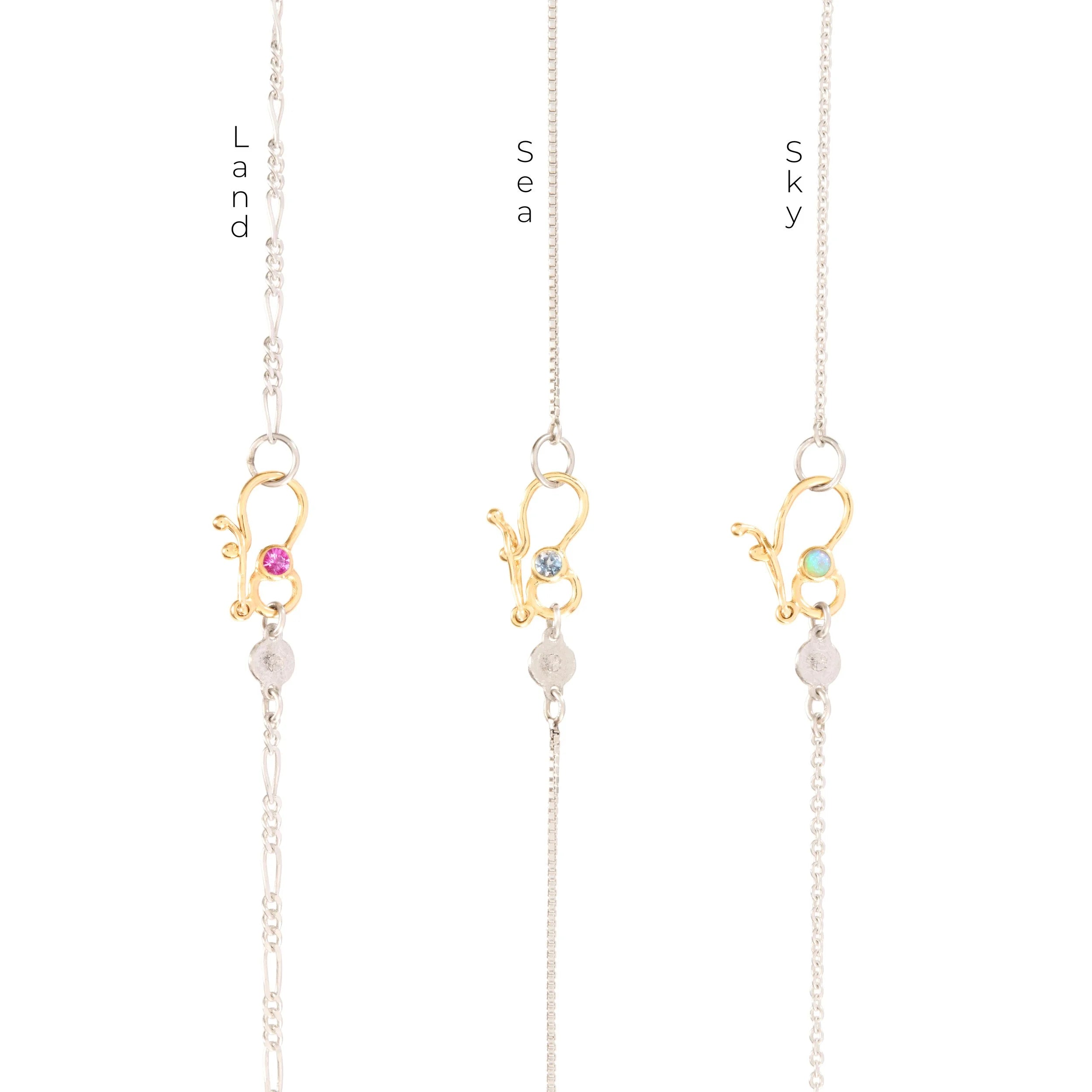 Three gold necklaces with gemstone pendants on a white background