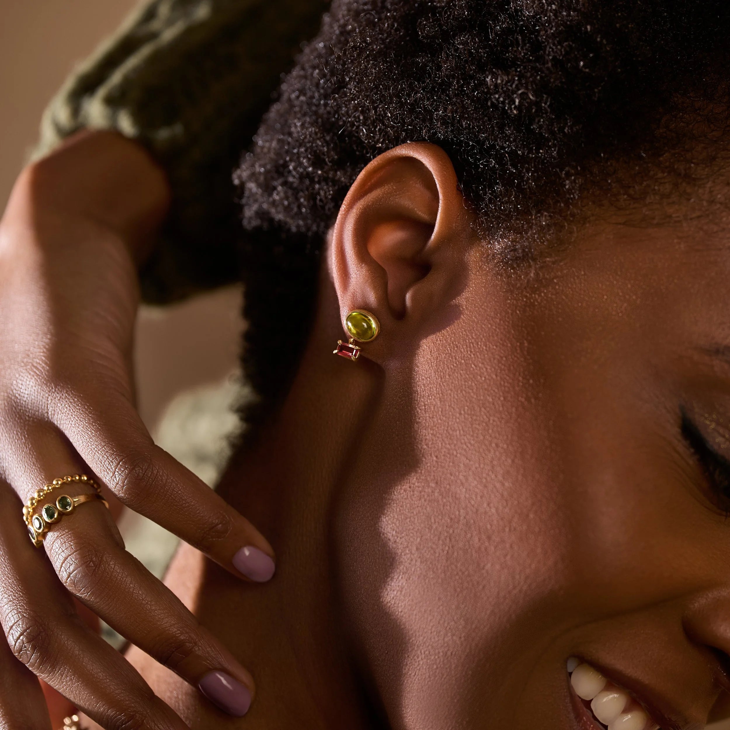 Close-up of a person wearing gold earrings and rings with a blurred background