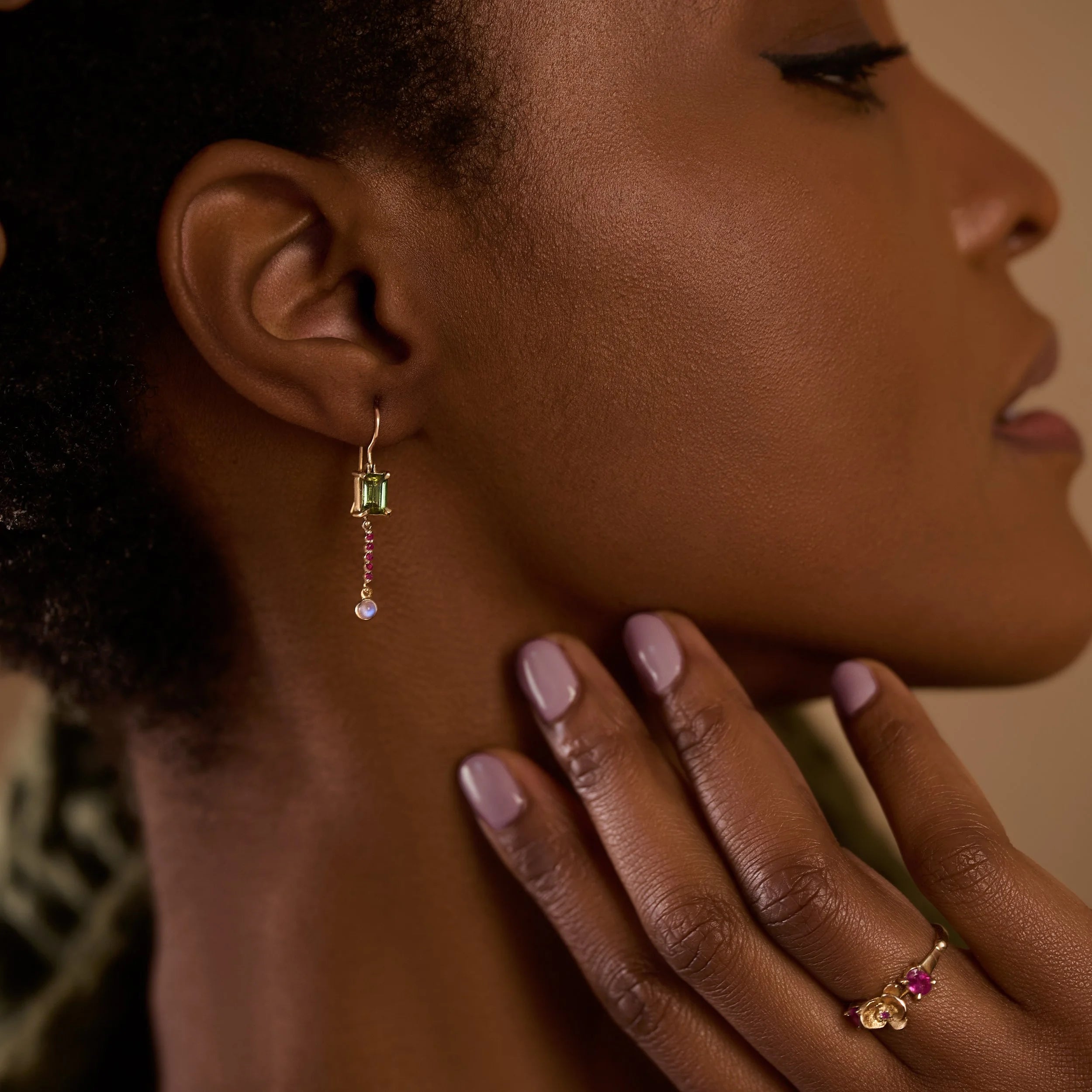 Close-up of a woman wearing an earring with a hand touching her neck.
