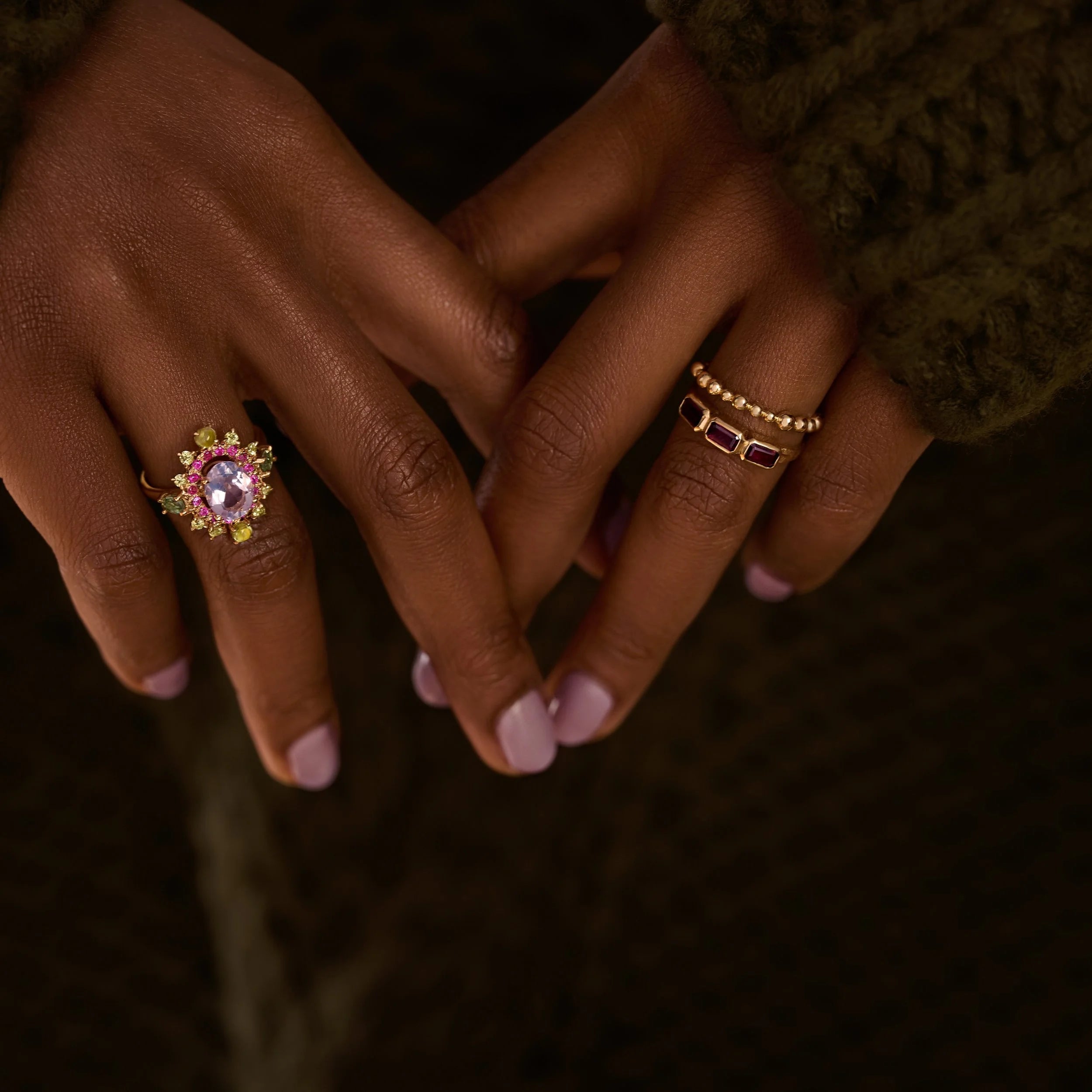 Close-up of hands with decorative rings on a dark background