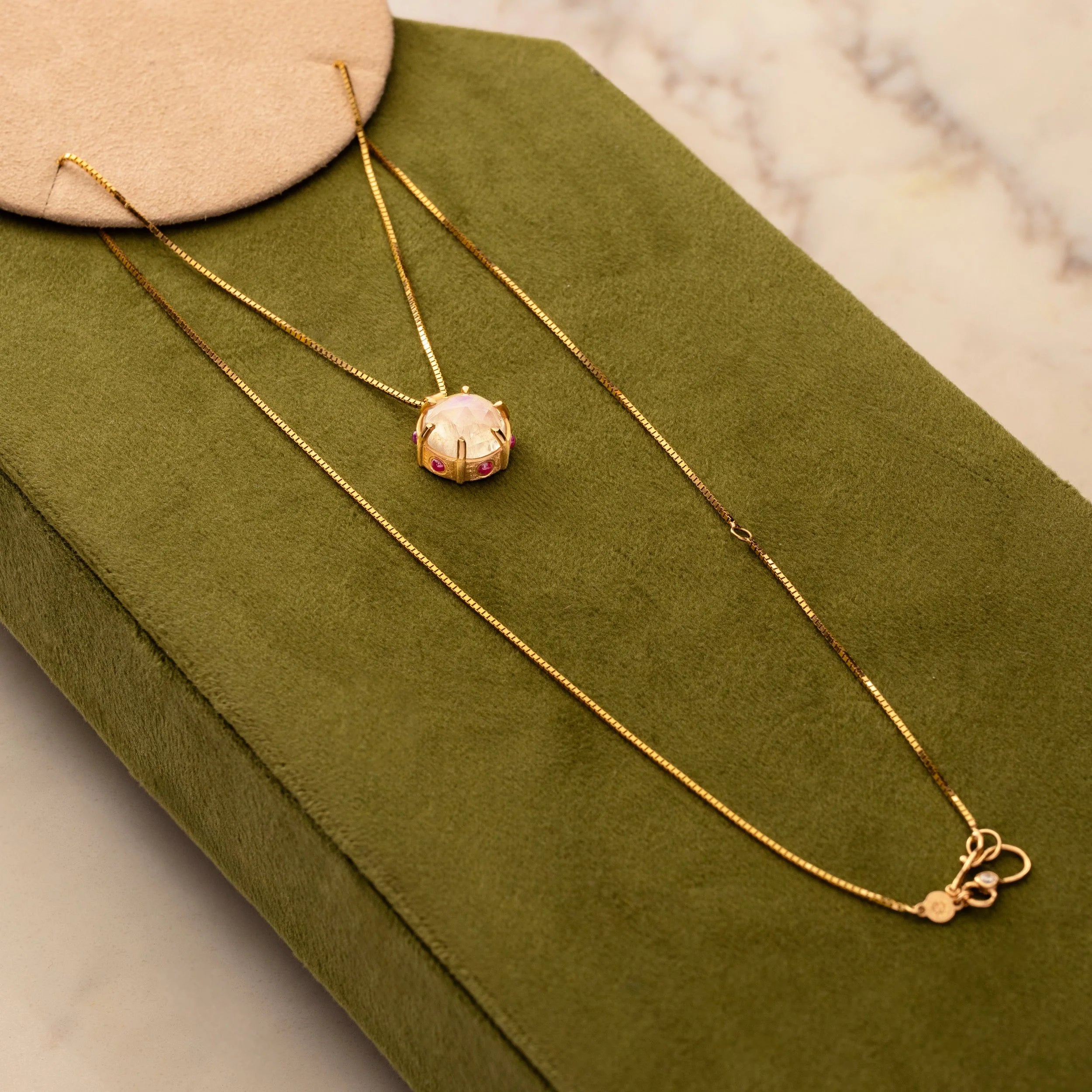 Gold necklace with a pendant on a green jewelry box