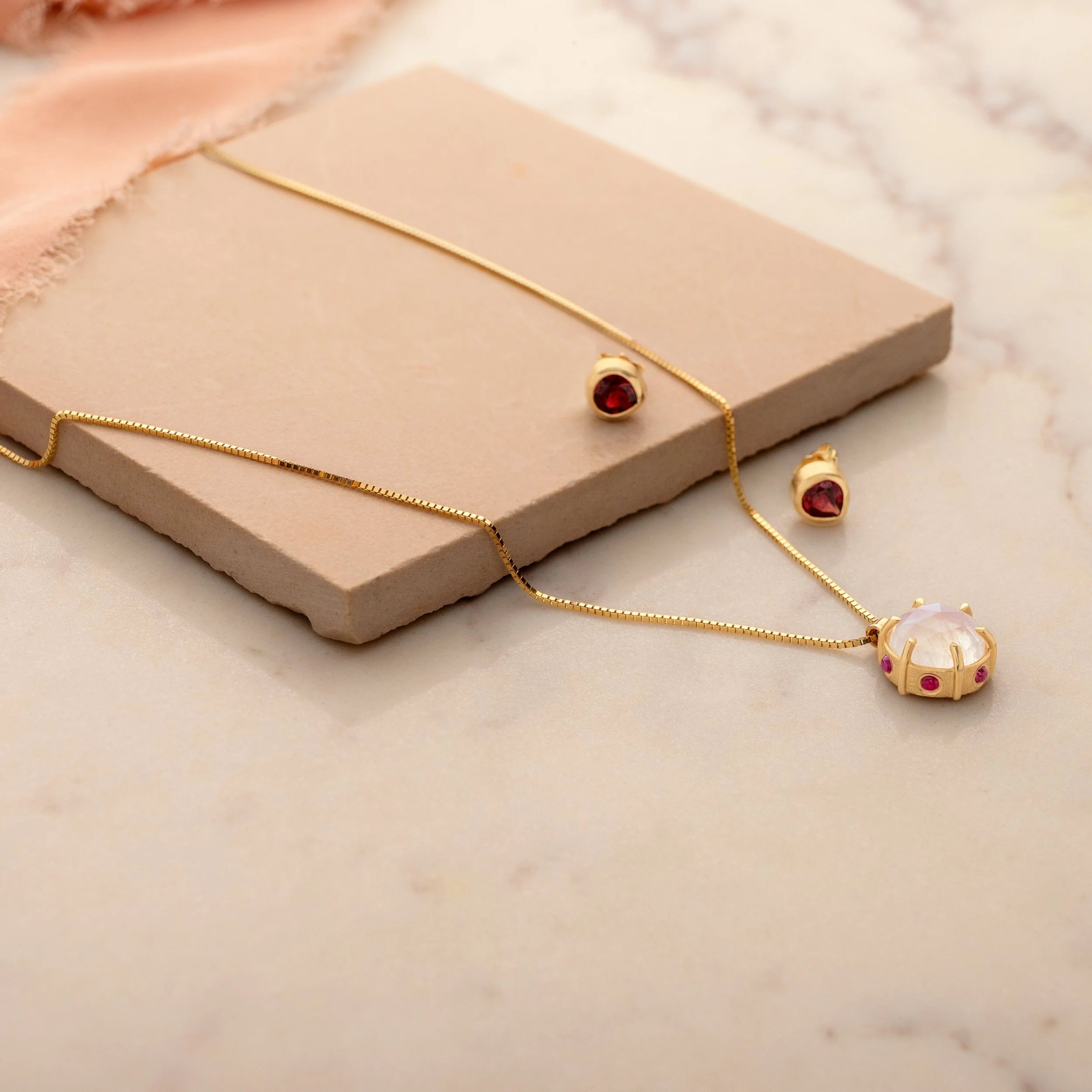 Gold jewelry set with necklace and matching earrings on a marble surface