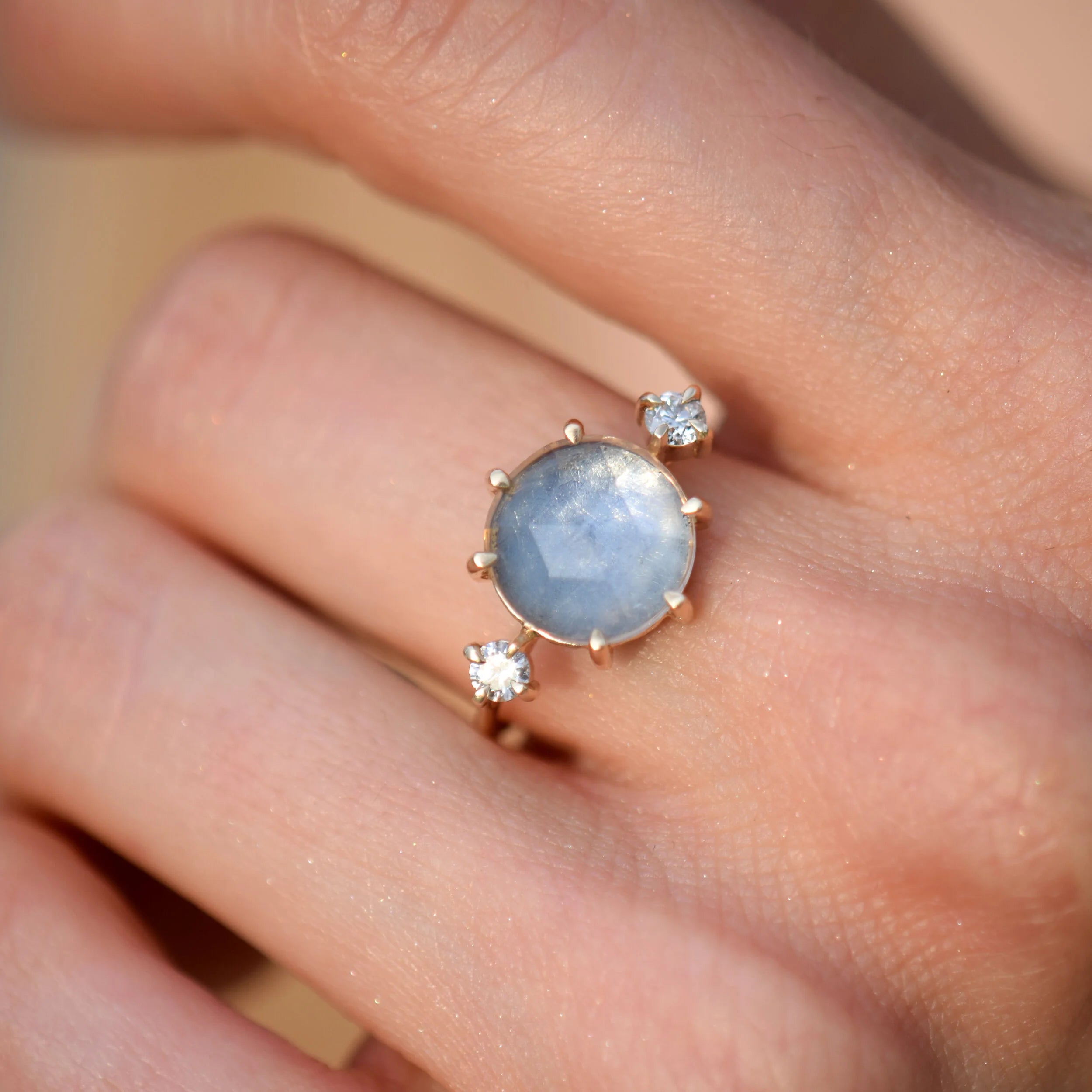 Ring with a blue gemstone and smaller diamonds on a finger