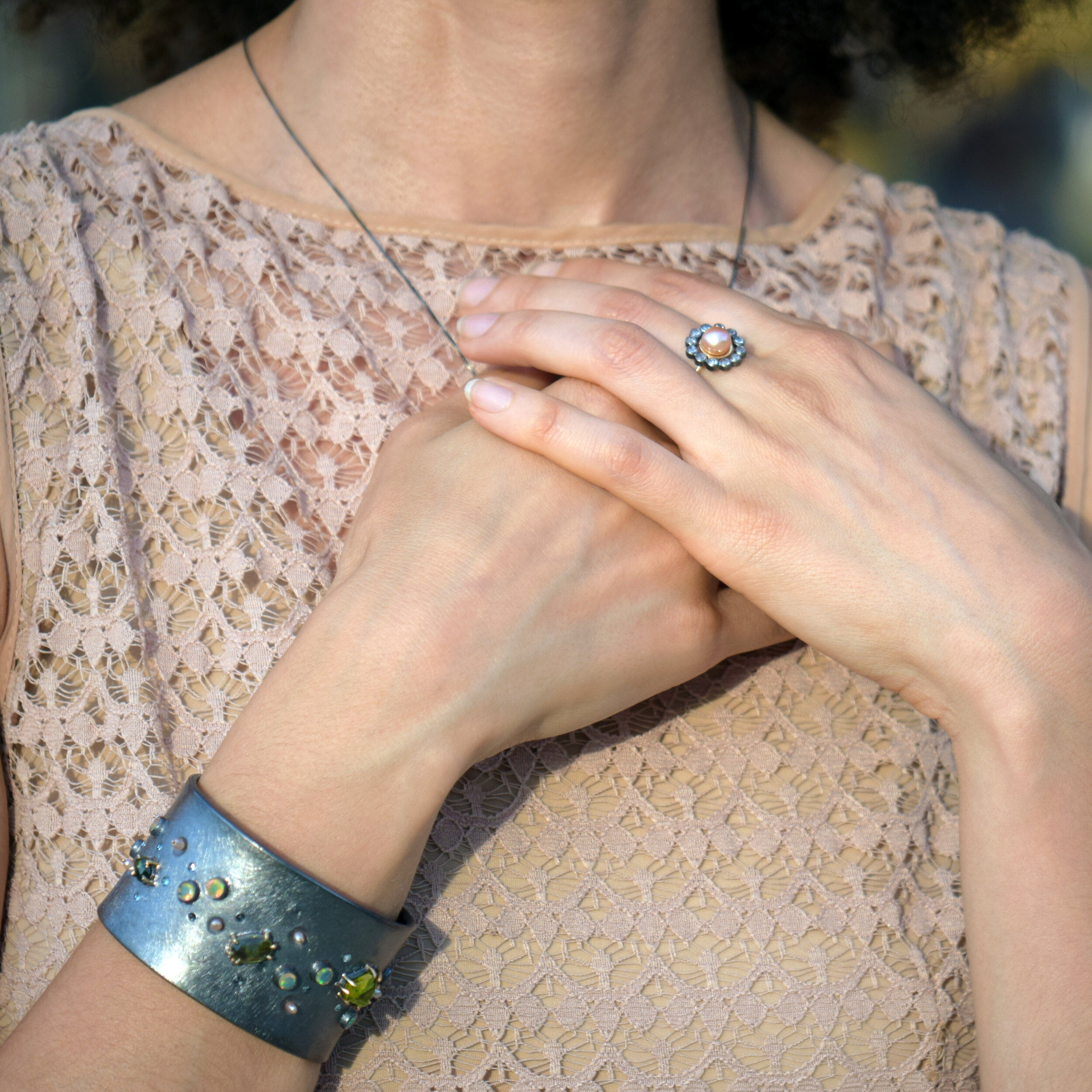 Close-up of a person wearing a ring and bracelet, with a blurred background