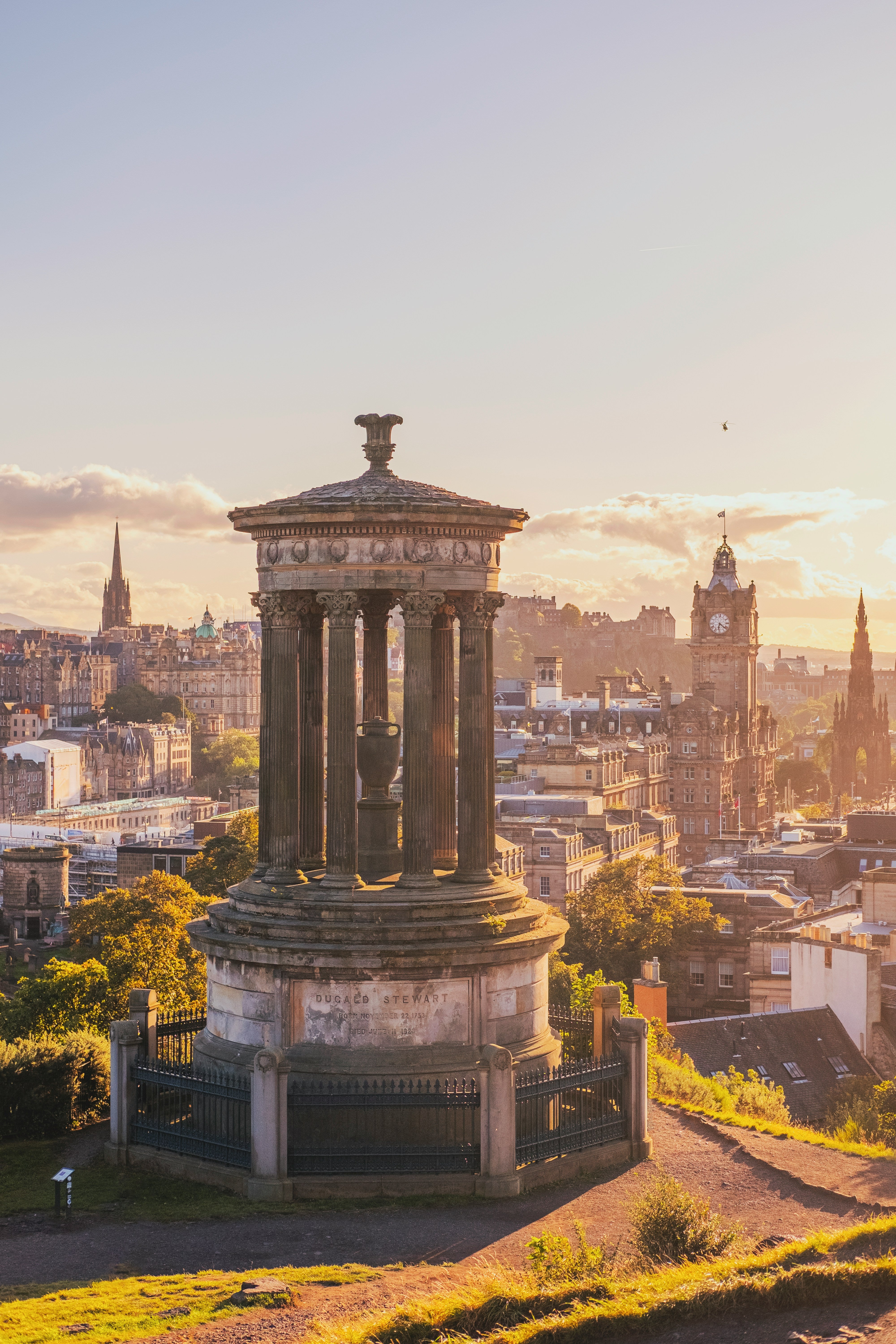 Historic monument with cityscape of Edinburgh in the background during sunset