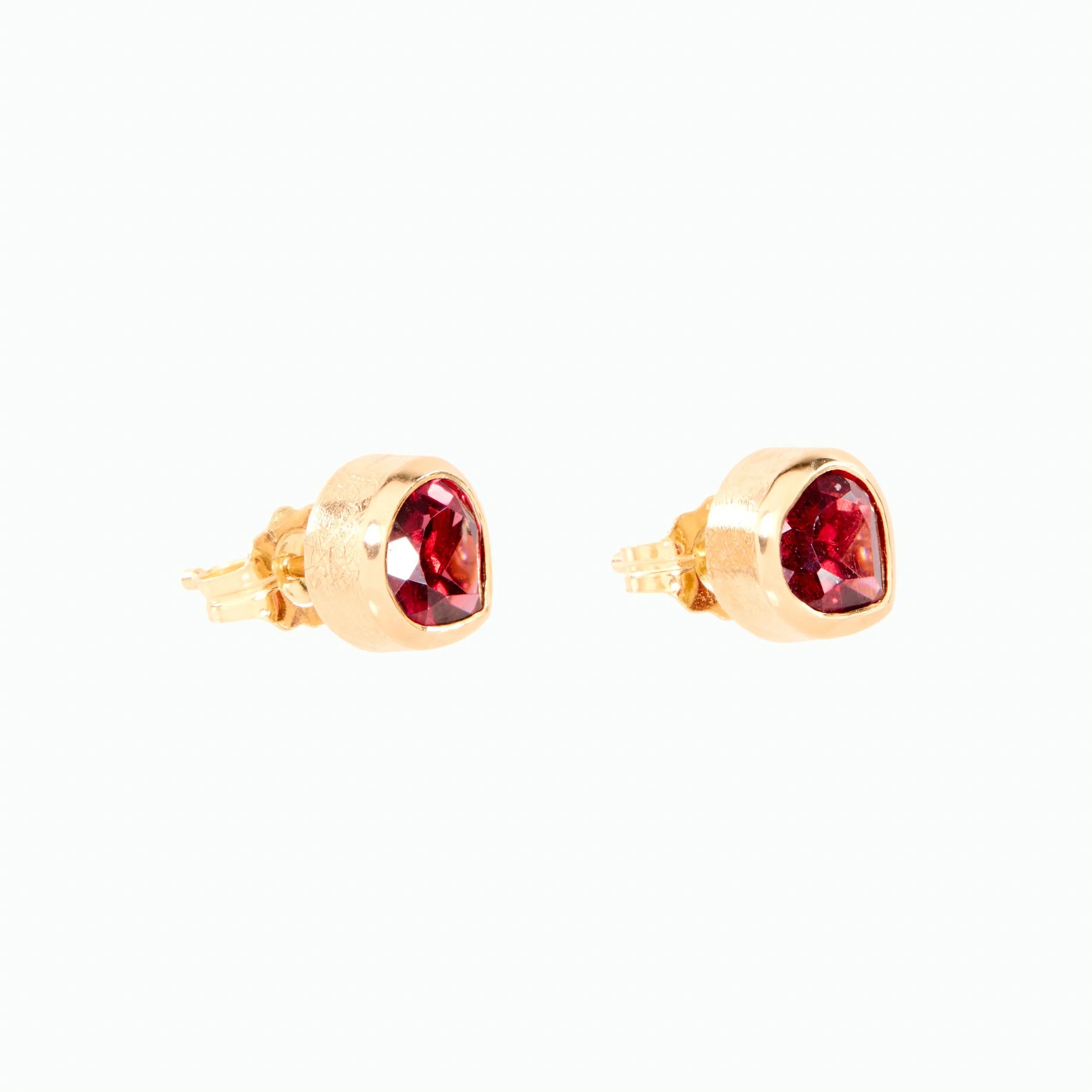 Gold earrings with red gemstones on a white background