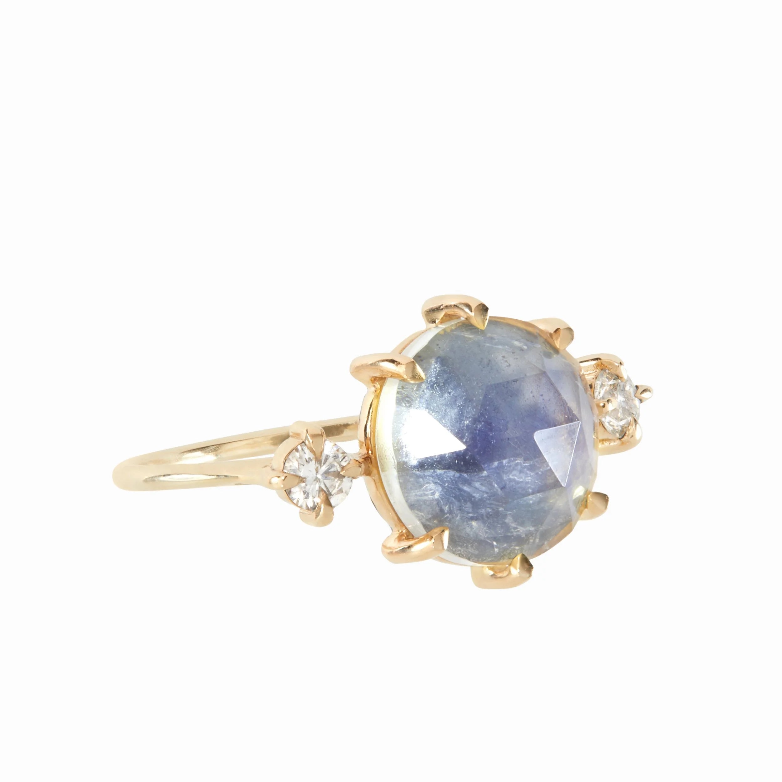 Gold ring with a blue gemstone and smaller diamonds on a white background