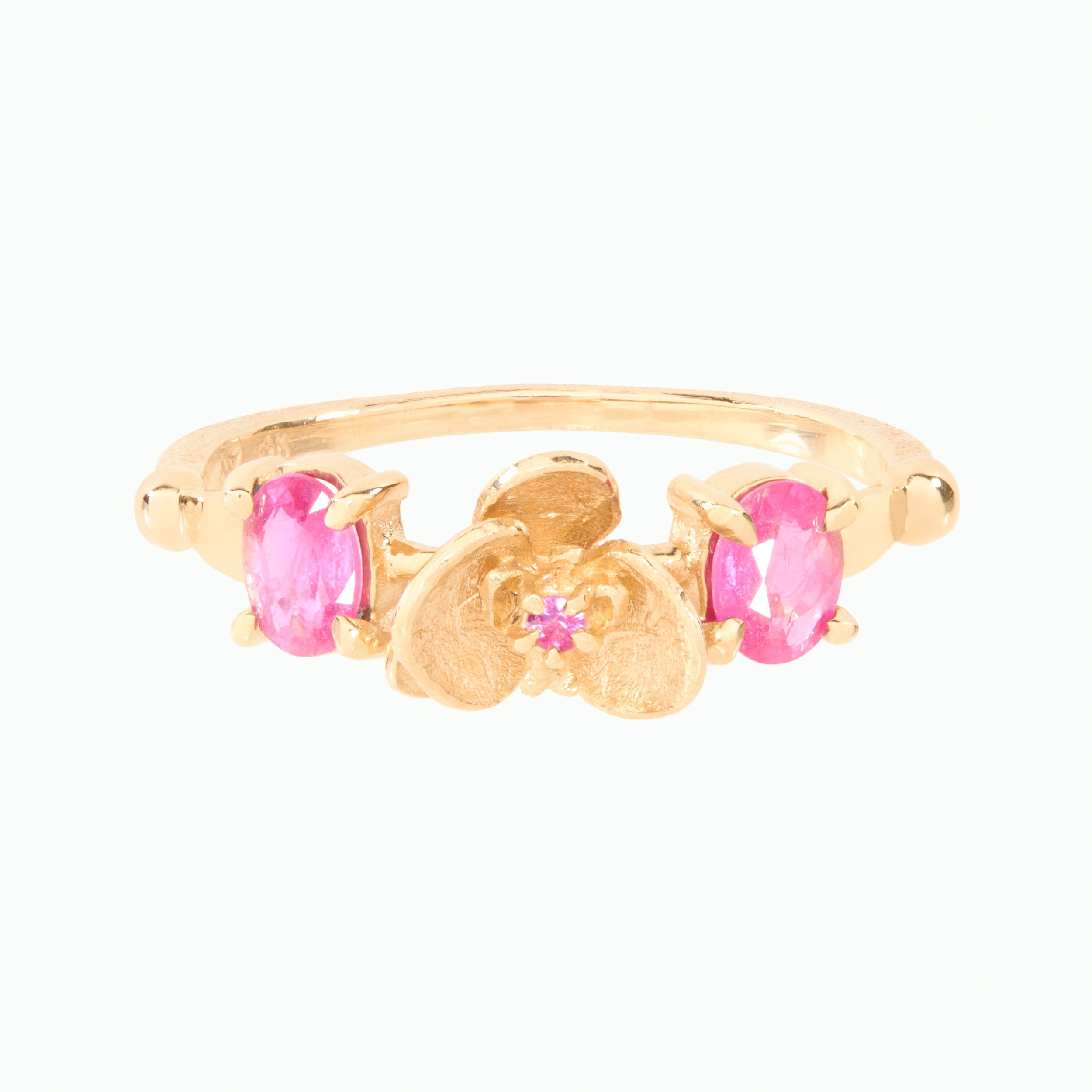 Gold ring with pink gemstones on a white background