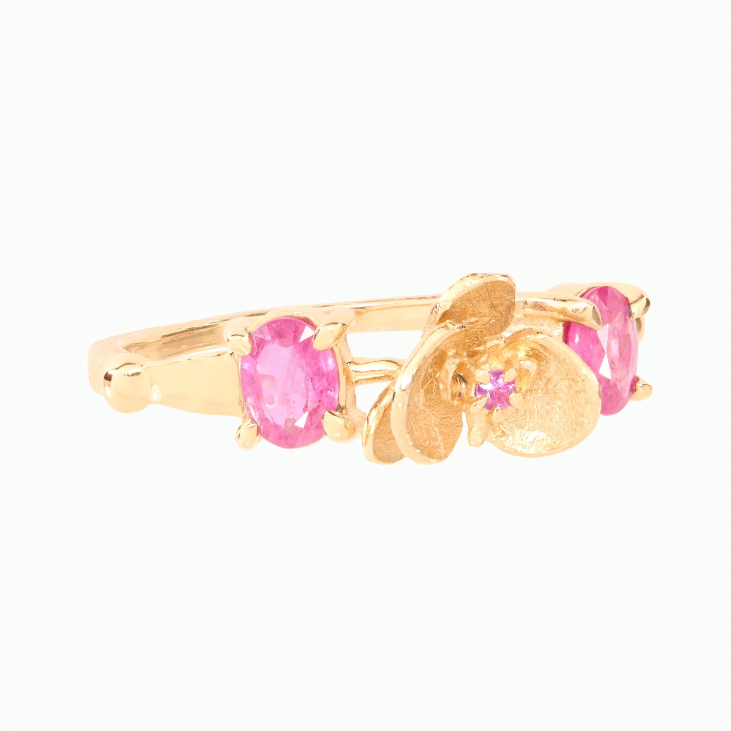 Gold ring with pink gemstones on a white background