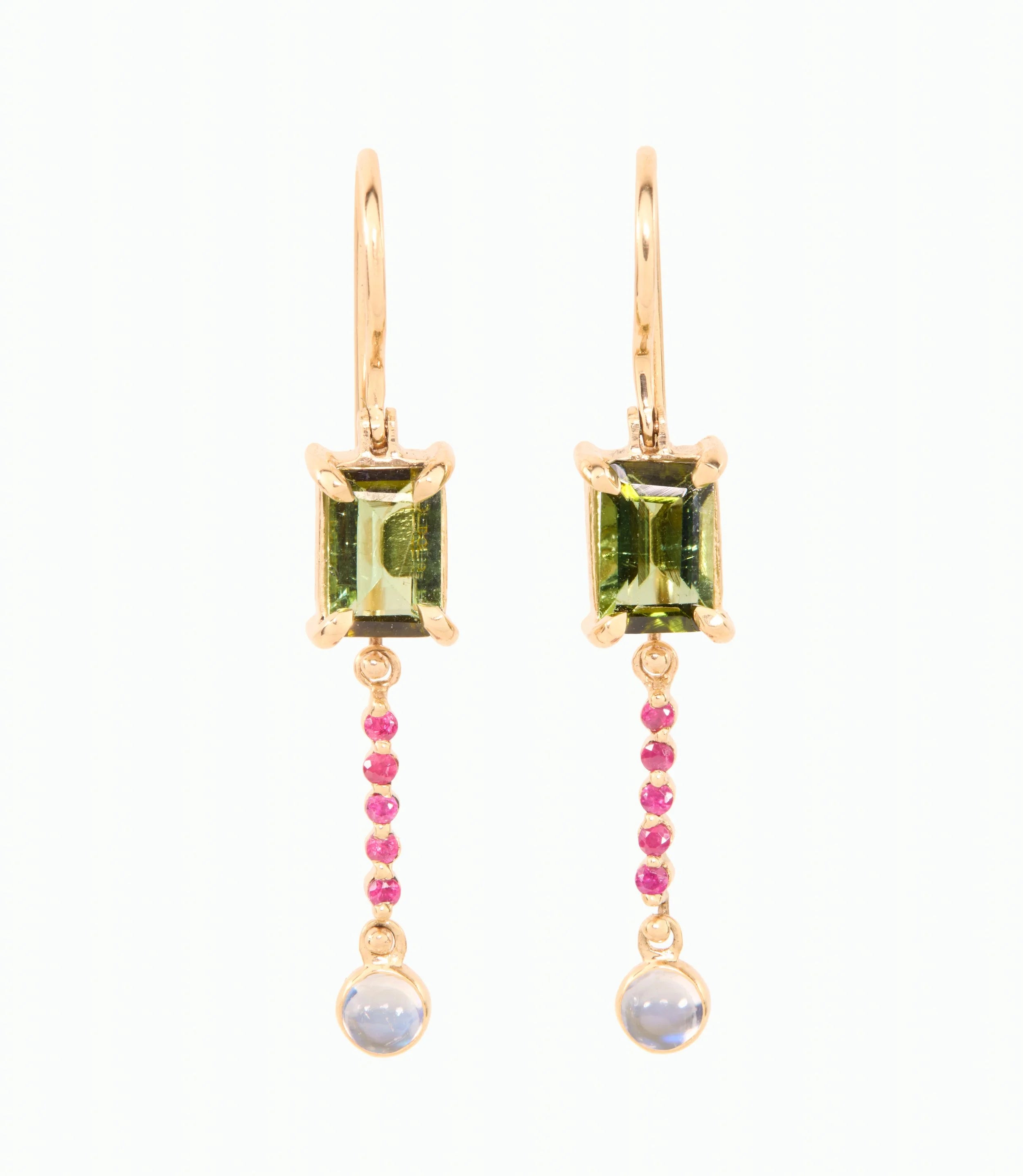 Gold earrings with green gemstones and pink rubies on a white background