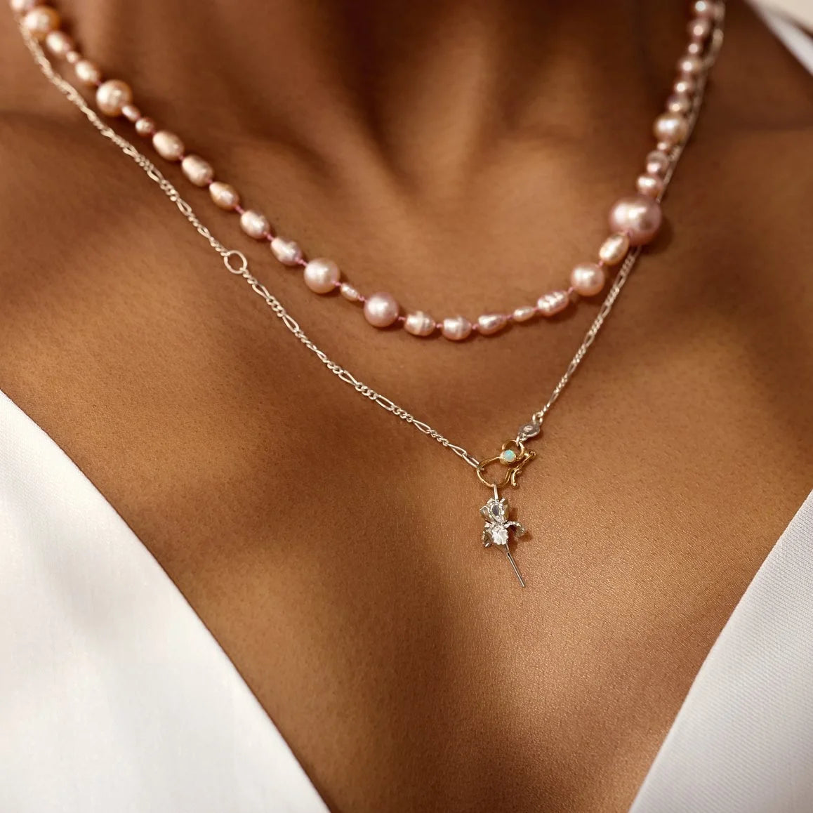 Two necklaces on a person's neck with a focus on the pearl necklace.
