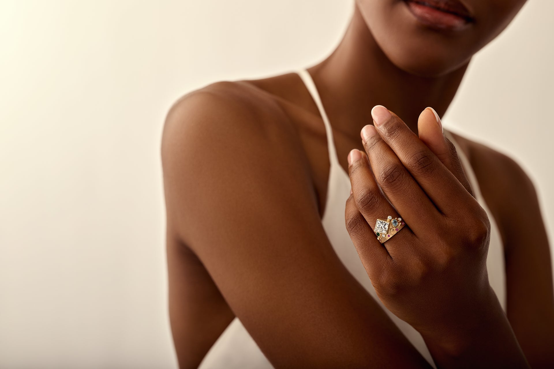 Woman wearing a diamond ring on her finger against a neutral background